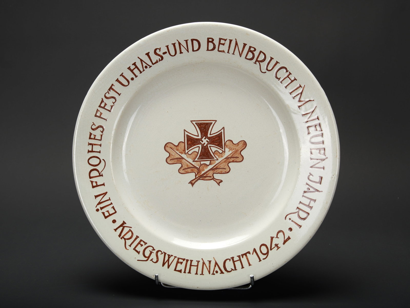 Plat Noel de guerre 1942. 1942 War Christmas platter.: Plat Noel de guerre 1942. En ceramique. Decors de feuilles de chene et croix de fer. Marquages sur le pourtour du plat Ein Frohes Fest U Hals und Beinbruch im Neuen Jahr Kriegsweihnacht 92. Un eclat