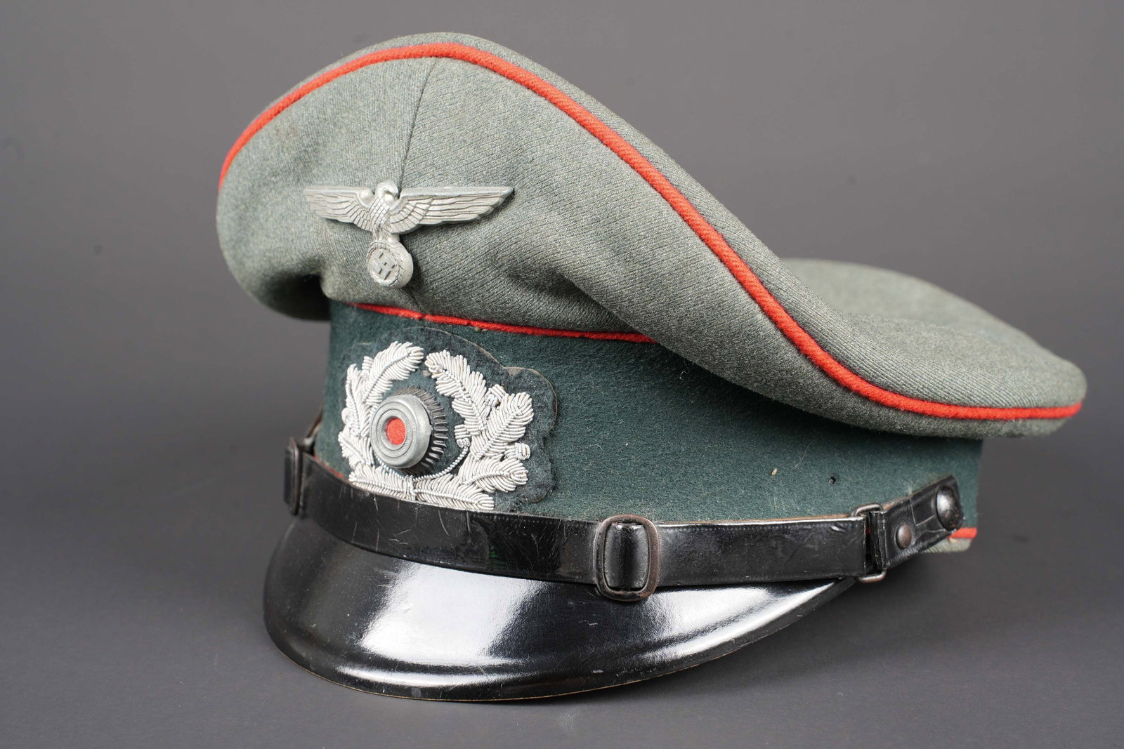 Casquette artillerie WH. German cap.: Casquette de l artillerie WH. En drap Feldgrau. Legerement deformee. Triple lisere rouge de l artillerie. Aigle metallique. Cocarde en cannetille argent. Les insignes n ont pas ete demontes afin de