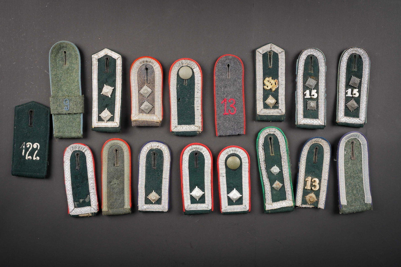 Pattes d epaule allemande. German shoulder taps.: Pattes d epaule allemande. Comprenant une paire de pattes d epaule d unterfeldwebel, un bouton grenele est present, fortement mite, lisere rouge de l artillerie. Une patte d epaule d Unteroffizier de 