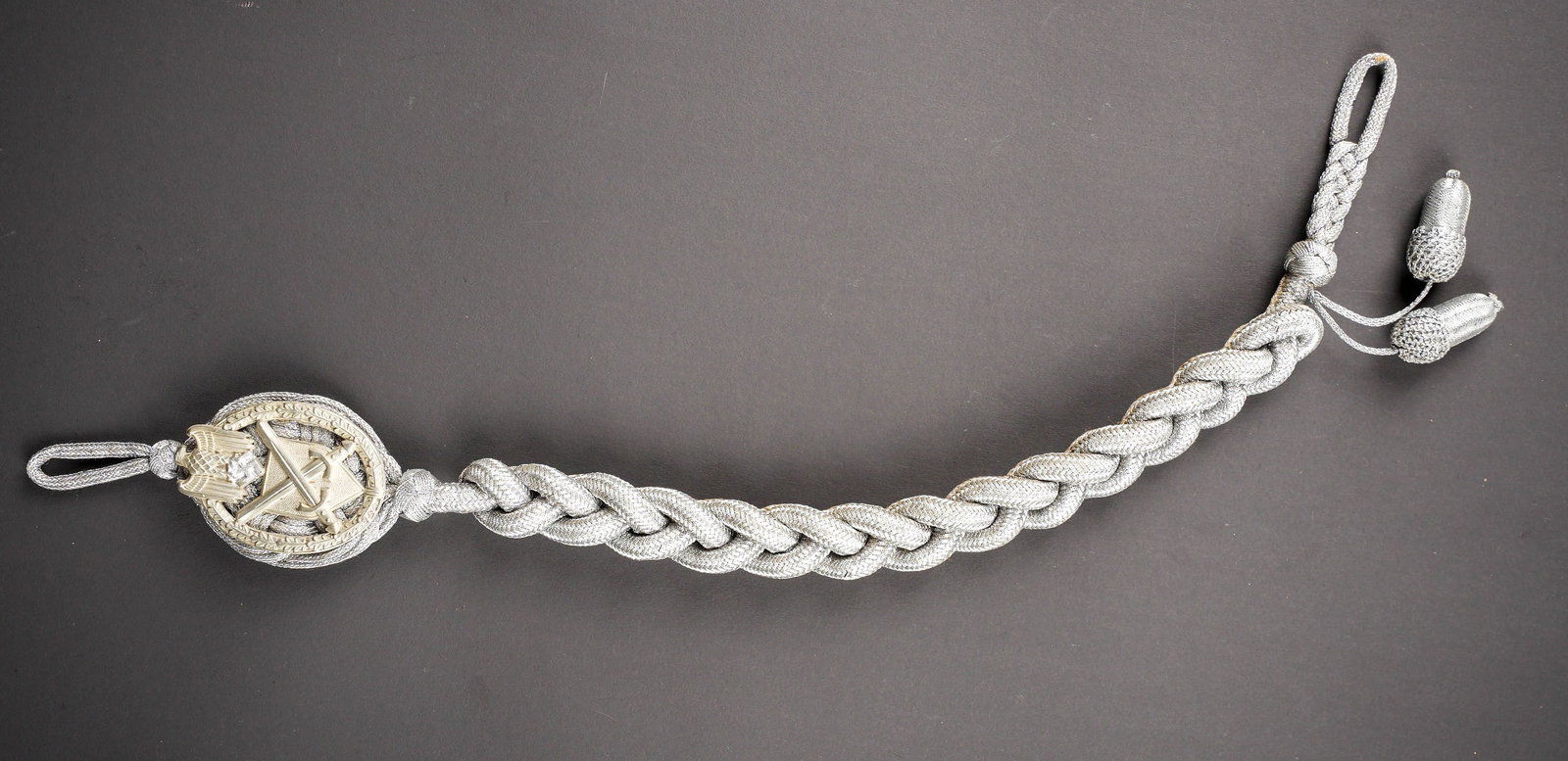 Cordon de tireur Heer. Heer marksman?s lanyard.: Cordon de tireur Heer. Fils argentes tresses. Plaque en metal, fixee d origine sur le cordon. Deux glands argentes. Dos de la piece double en drap Feldgrau et satinette grise. A noter une certaine usu