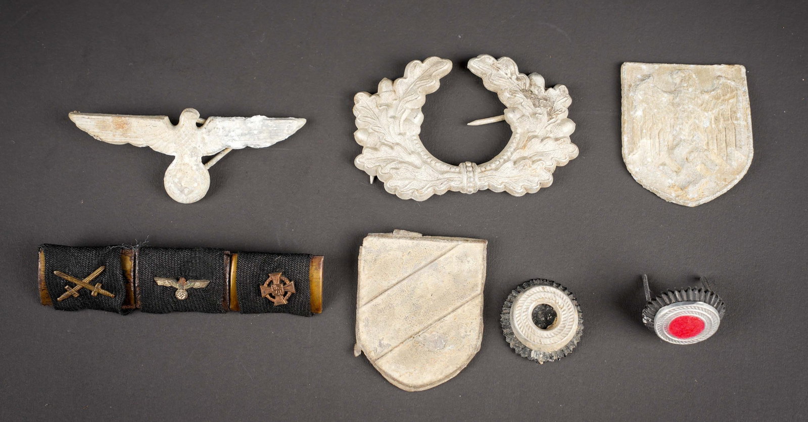 Insignes de fouille allemand. Excavated German insignia.: Insignes de fouille allemand. Comprenant une feuille de chene en metal, un aigle de coiffure wehrmacht, une paire d insignes de coiffure de l Afrikakorps. Une cocarde. Une barrette de trois rubans de