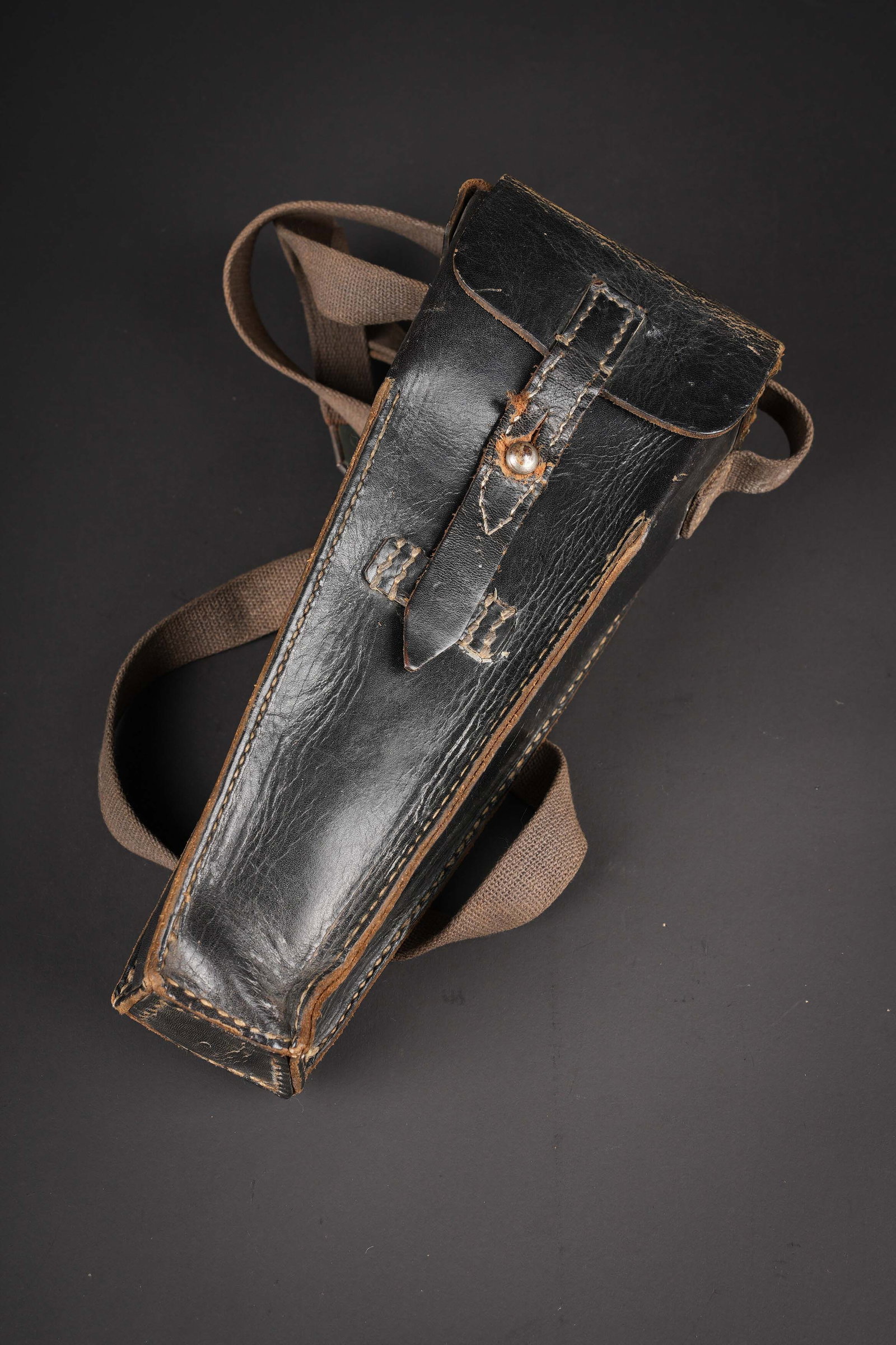 Housse de lance grenade allemand. German grenade launcher cover.: Housse de lance grenade allemand. En cuir noir. La sangle de fermeture est presente, ainsi que la sangle de transport en toile. Bouclerie marquee SHB. Le passant au ceinturon est complet. Fabrication