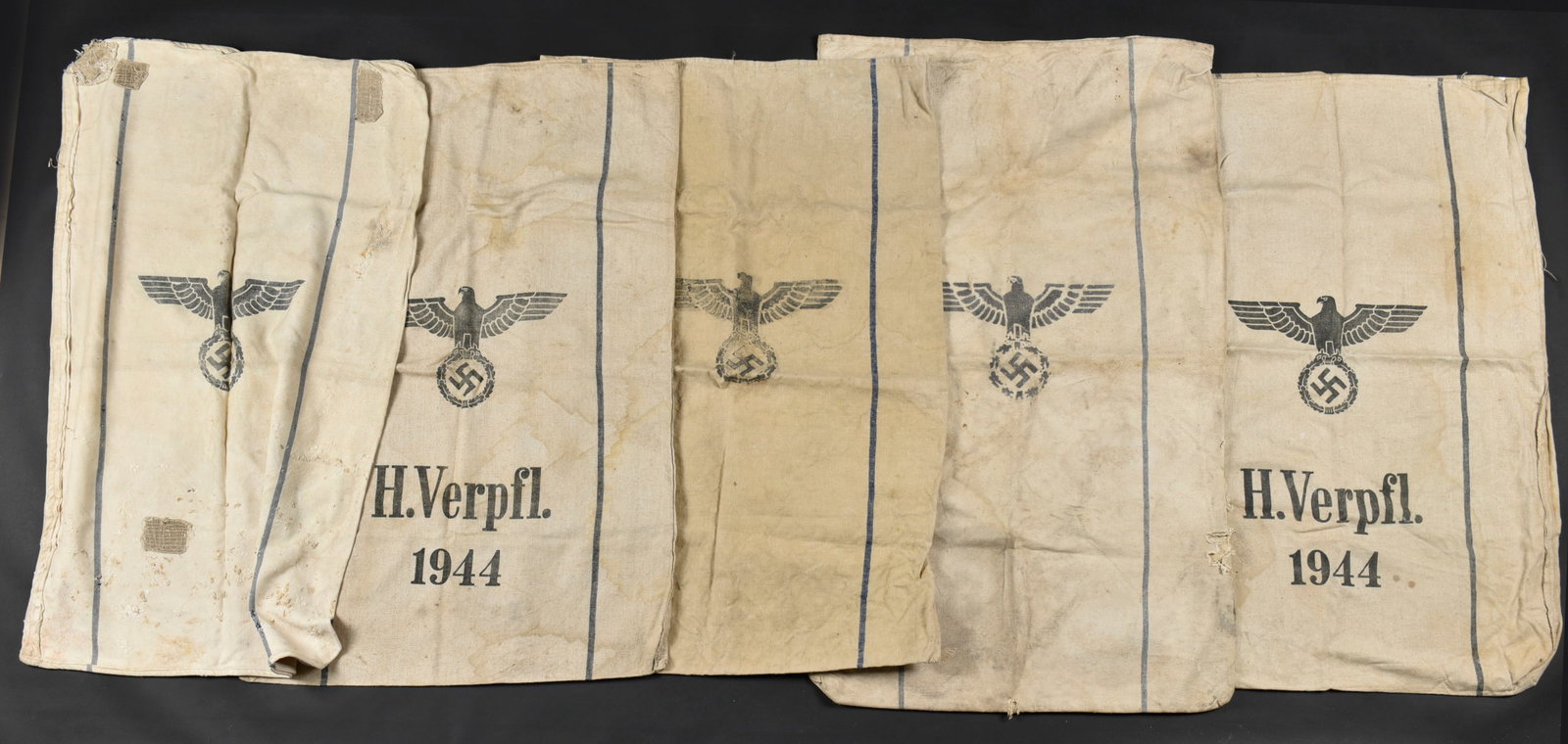 Sacs a denrees allemands. German ration bags.: Sacs a denree allemand. Cinq sacs en toile blanche et liseres bleus. Dates 1939, 1944, 1940 et 1941. A noter une certaine usure et patine des pieces, ainsi que des taches, accrocs et reparations.