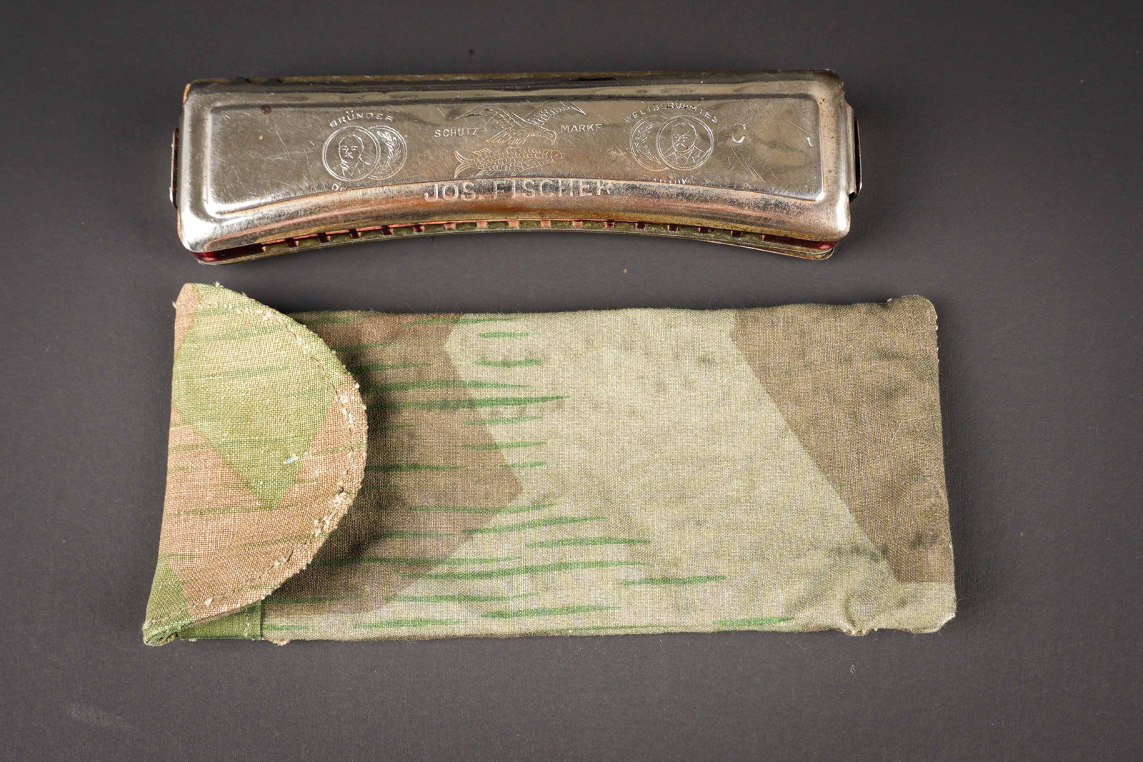 Harmonica allemand. German harmonica.: Harmonica allemand. En metal, fonctionnel, marque Militar Musik. Housse fantaisie probablement une fabrication terrain, en toile camoufle eclat, bouton pression fonctionnel. A noter une certaine
