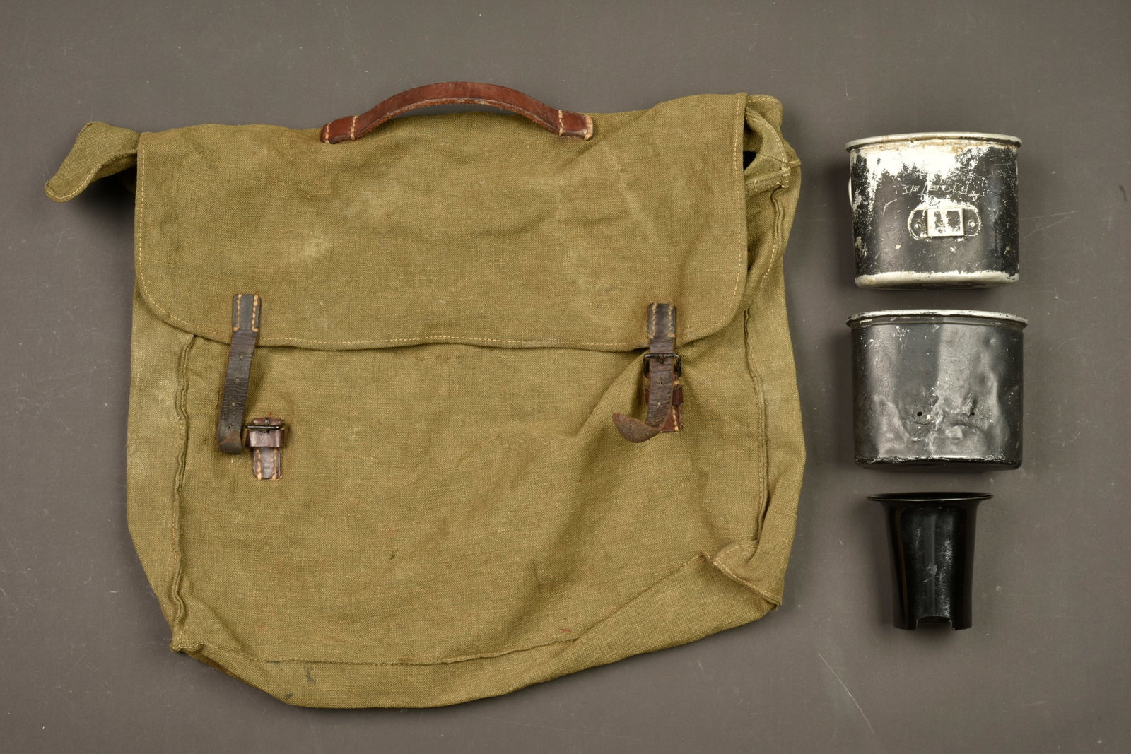 Equipement allemand. German equipment: Equipement allemand. Comprenant une sacoche de permissionnaire en forte toile feldgrau et cuir noir. La poignee de transport et les sangles de fermeture sont completes. Sans marquages visibles. Un