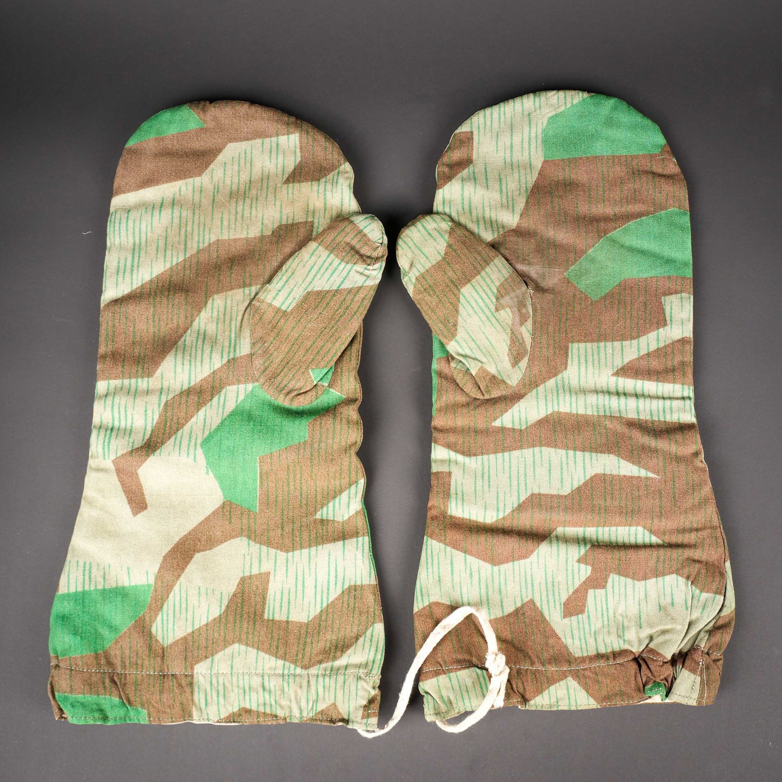 Gants reversibles camoufles. German camouflaged gloves: Moufles reversibles camoufles. En tissu coton eclat. Paire homogene. Reversible blanc. Les cordons sont presents, mais incomplets. Marquages RBNr illisibles A noter une legere usure et patine des