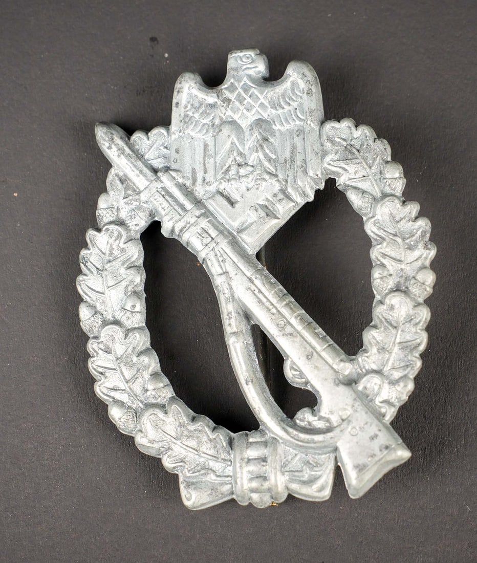 Infanterie-Sturmabzeichen. German insignia: Infanterie-Sturmabzeichen. En metal. Fabrication en creux. Couleur argent a 70%. Attache complete couleur bronze. Sans marquages visibles. A noter une certaine usure et patine de la piece. Etat II+.