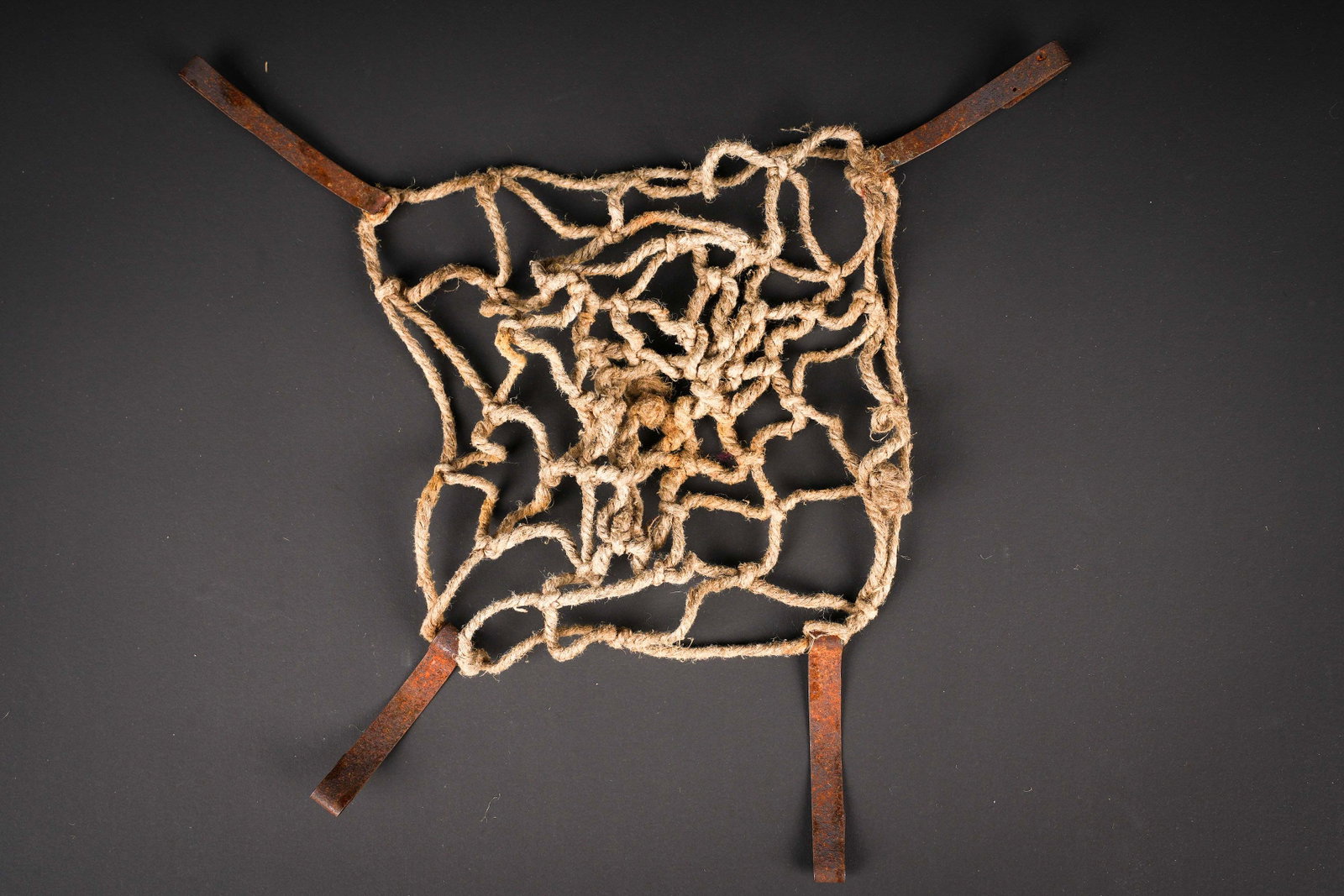 Filet de casque. German helmet net.: Filet de casque allemand. Fabrication artisanale en cordelette. Les cordelettes se sont retractees avec le temps. Trois pattes de fixation au cerclage. Celles-ci sont fortement oxydees. A noter une
