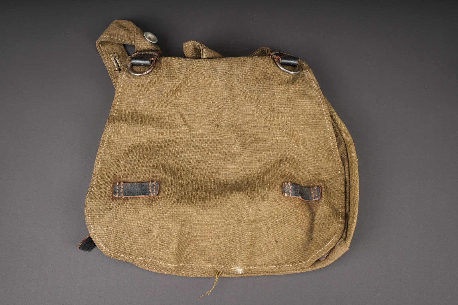 Sac a pain allemand. German bread bag.: Sac a pain de la Heer. En epaisse toile Feldgrau et cuir noir. Fabrication KKS 42. Les boutons sont presents. A noter une certaine usure et patine de la piece, ainsi que quelques taches et accrocs.