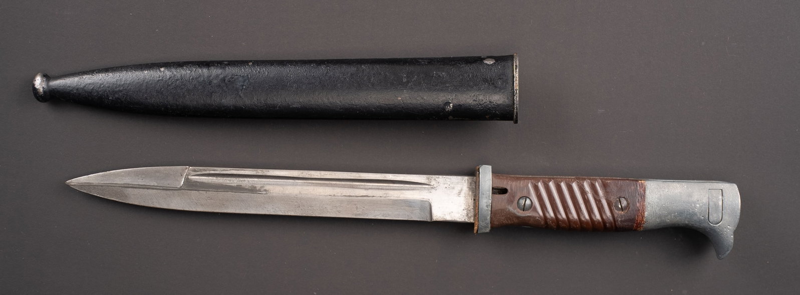 Baionnette allemande. German bayonet: Baionnette allemande. Garniture en metal, plaquettes en bakelite marron, nettoyees et repeinte. Fourreau oxyde et repeint. Lame usee. Sans marquages visibles. A noter une certaine usure et patine de