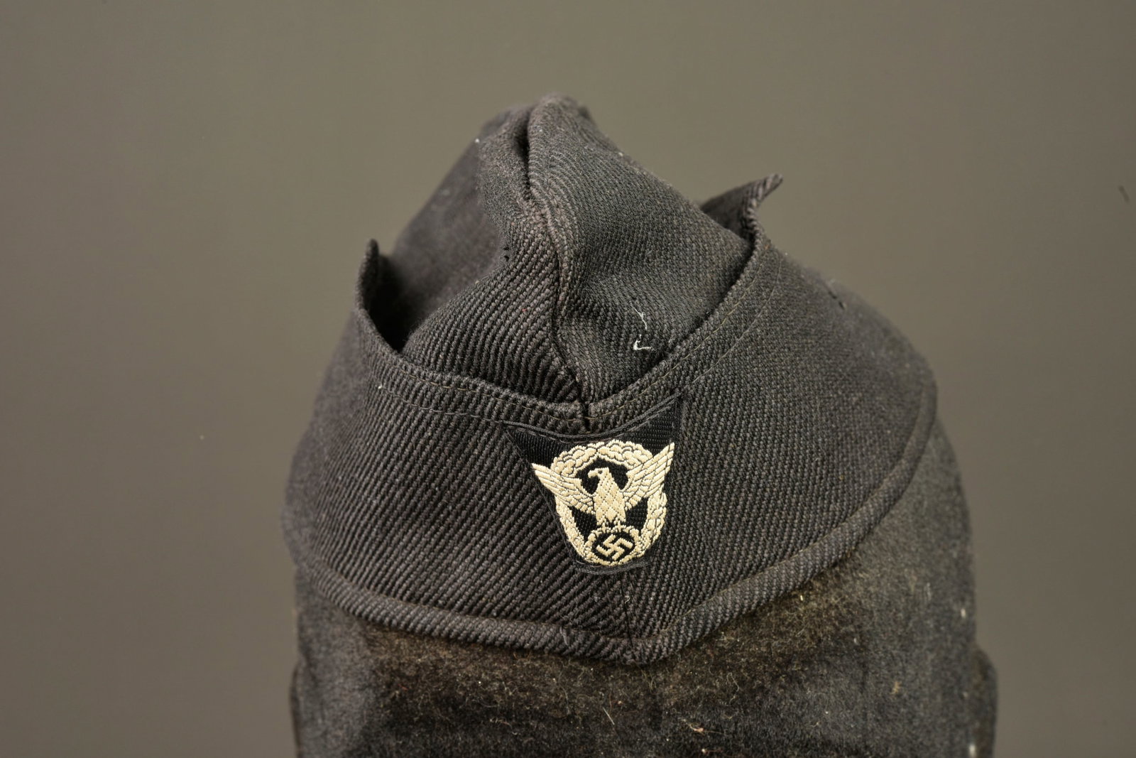 Calot Polizei. German Police garrison cap.: Calot Polizei. En tissu coton noir. Insigne Bevo Polizei sur fond noir, cousu machine. Interieur double en tissu coton noir. Etiquette blanche indiquant une taille 56. A noter une certaine usure et