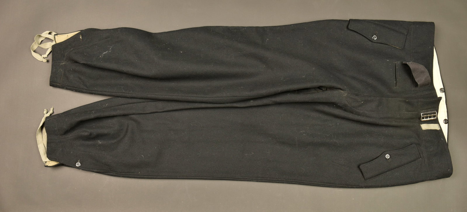 Pantalon Panzer Polizei. Panzer Polizei trousers.: Pantalon Panzer Polizei. En drap noir. Les cordons de serrage au bas des jambes sont presents. Doublure en tissu coton gris. Poches a rabat au niveau des hanches. Tous les boutons sont presents. Ceint