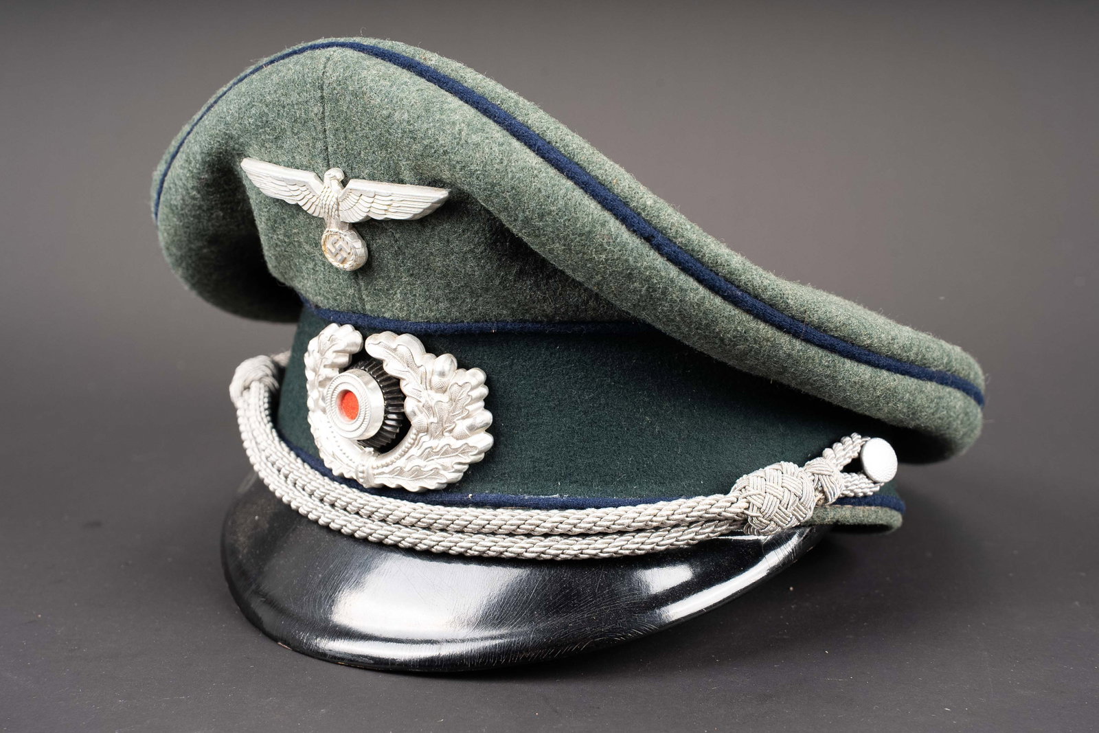 Casquette officier service de sante Heer. Heer medical service officer?s visor cap.: Casquette d officier des services de sante de la Heer. En drap Feldgrau. Triple lisere bleu des services de sante. Bandeau en drap vert fonce. Insignes metalliques. Les insignes n ont pas ete