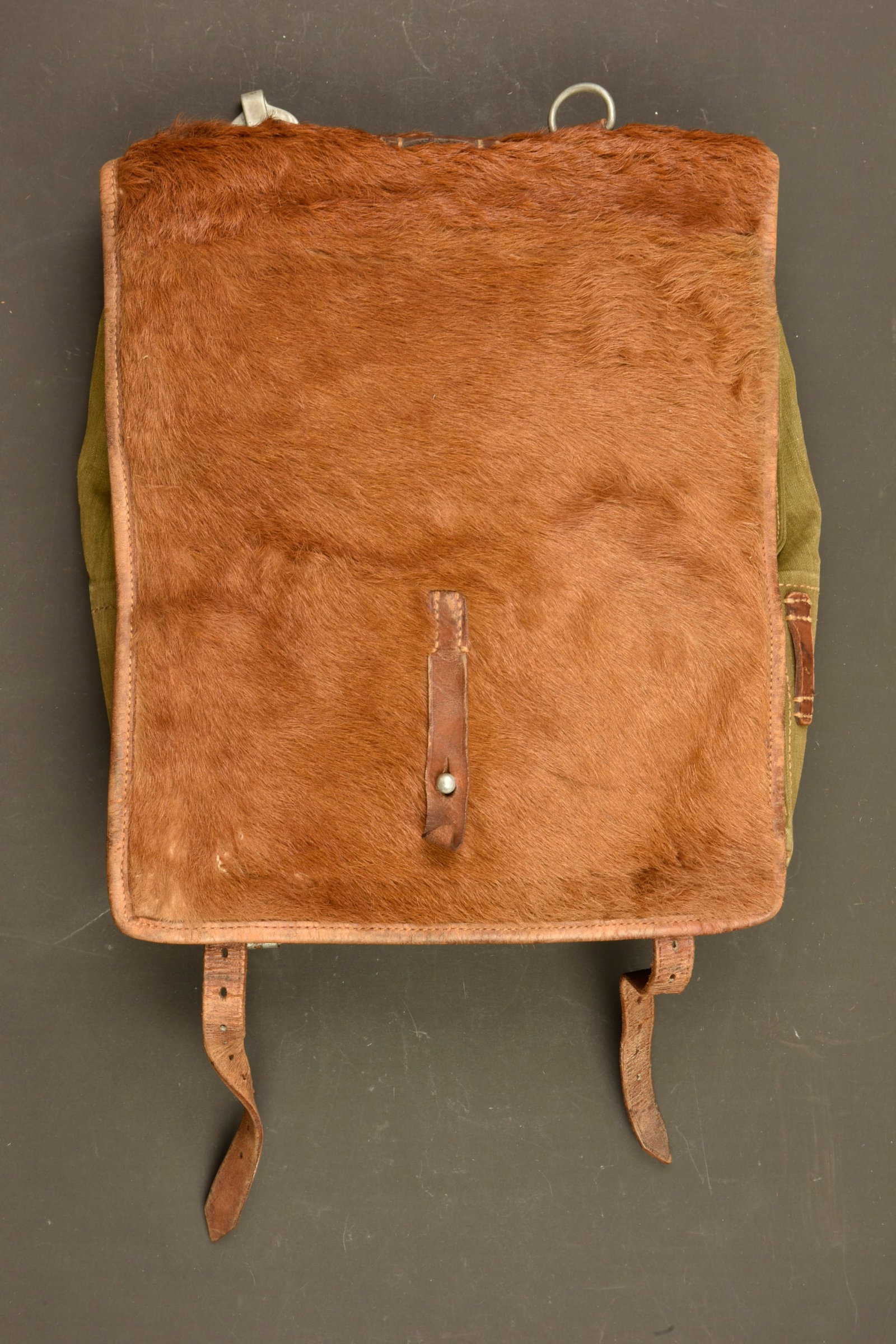 Sac a dos poils de vache. German Cowhide backpack.: Sac a dos poil de vache. En forte toile Feldgrau. Rabat recouvert de poils de vache rousse. La majorite des sangles sont presentes. Les bretelles sont manquantes. Les parties metalliques sont