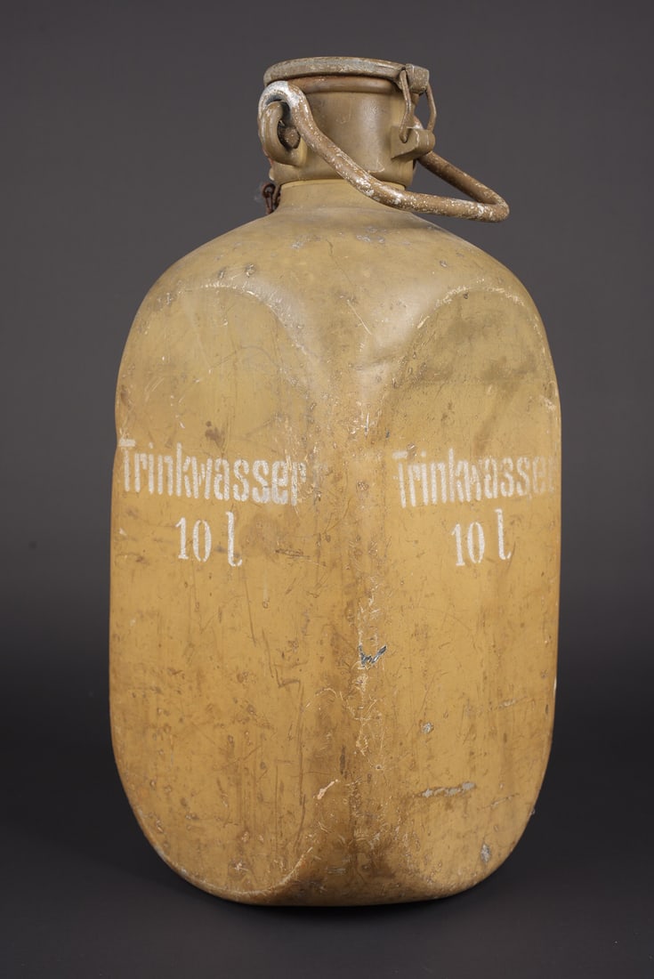Trinkwasser 10L. 10L drinking water container: Trinkwasser 10L. En metal. Peinture jaune sable a 70%. Beau marquages Trinkwasser 10L sur toutes les faces. Bouchon complet avec son crochet et sa chainette. Poignee de transport presente. Marquages