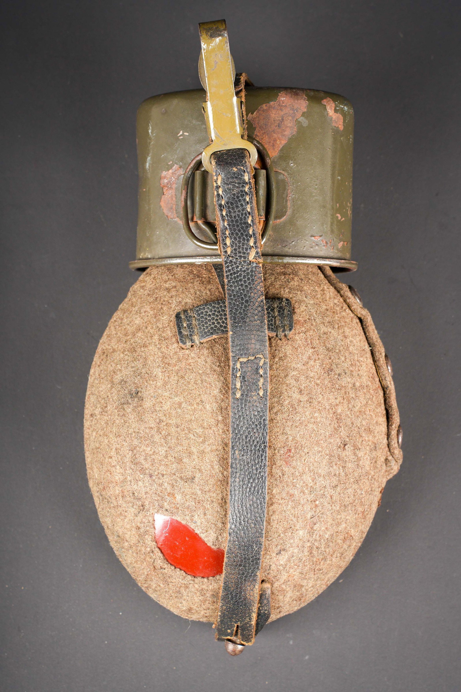 Gourde allemand. German water bottle.: Gourde allemande. En metal emaille rouge. Bouchon complet. Housse en forte toile Feldgrau, les boutons pressions sont fonctionnels. Harnais en cuir. Mousqueton fonctionnel. Quart en metal emaille