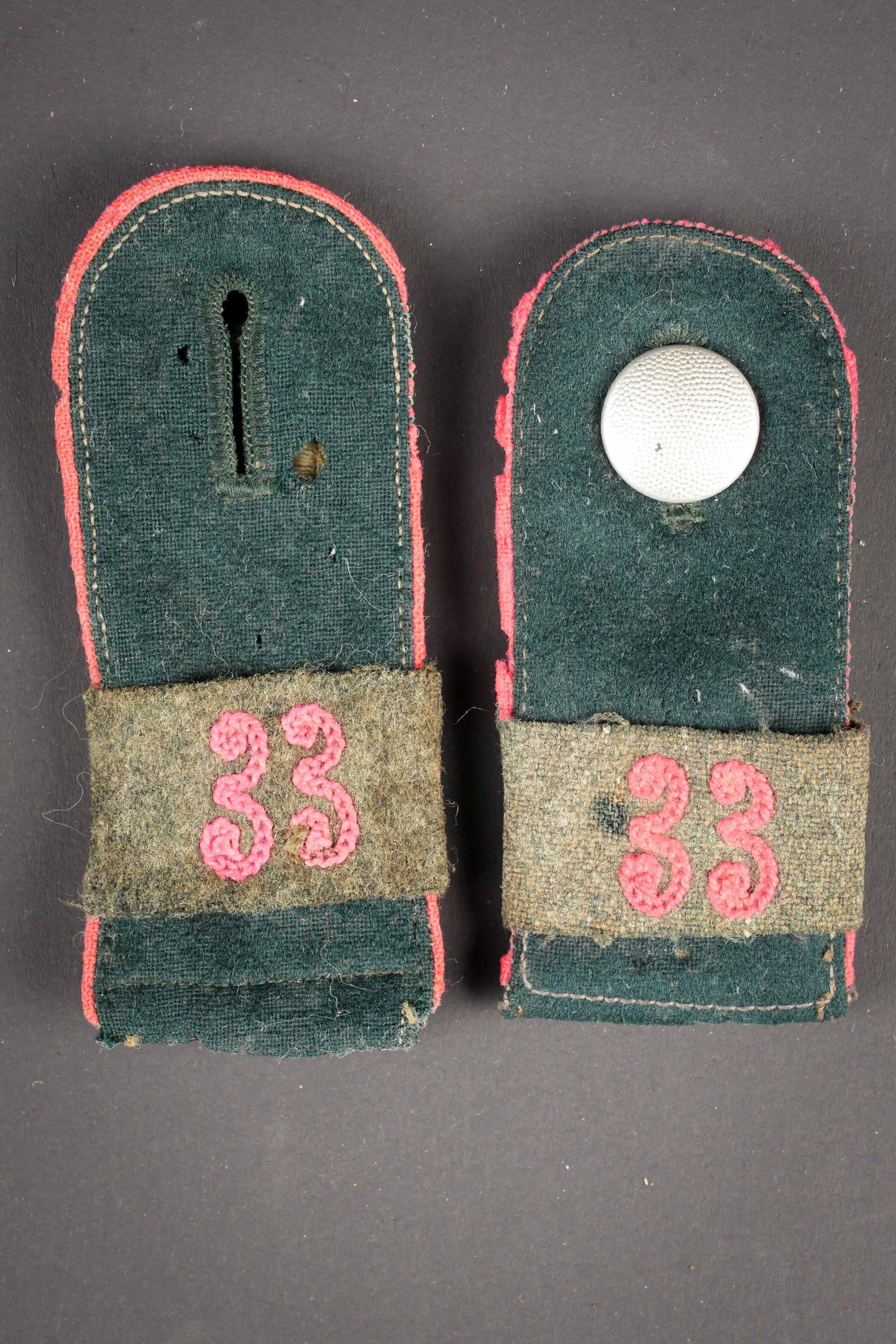 Pattes d epaule Panzer. German Panzer shoulder board.: Pattes d epaule Panzer. En drap vert fonce. Lisere rose. Un bouton grenele present. Passants en drap Feldgrau, brode en rose du chiffre 33. A noter une certaine usure et patine des pieces, ainsi que