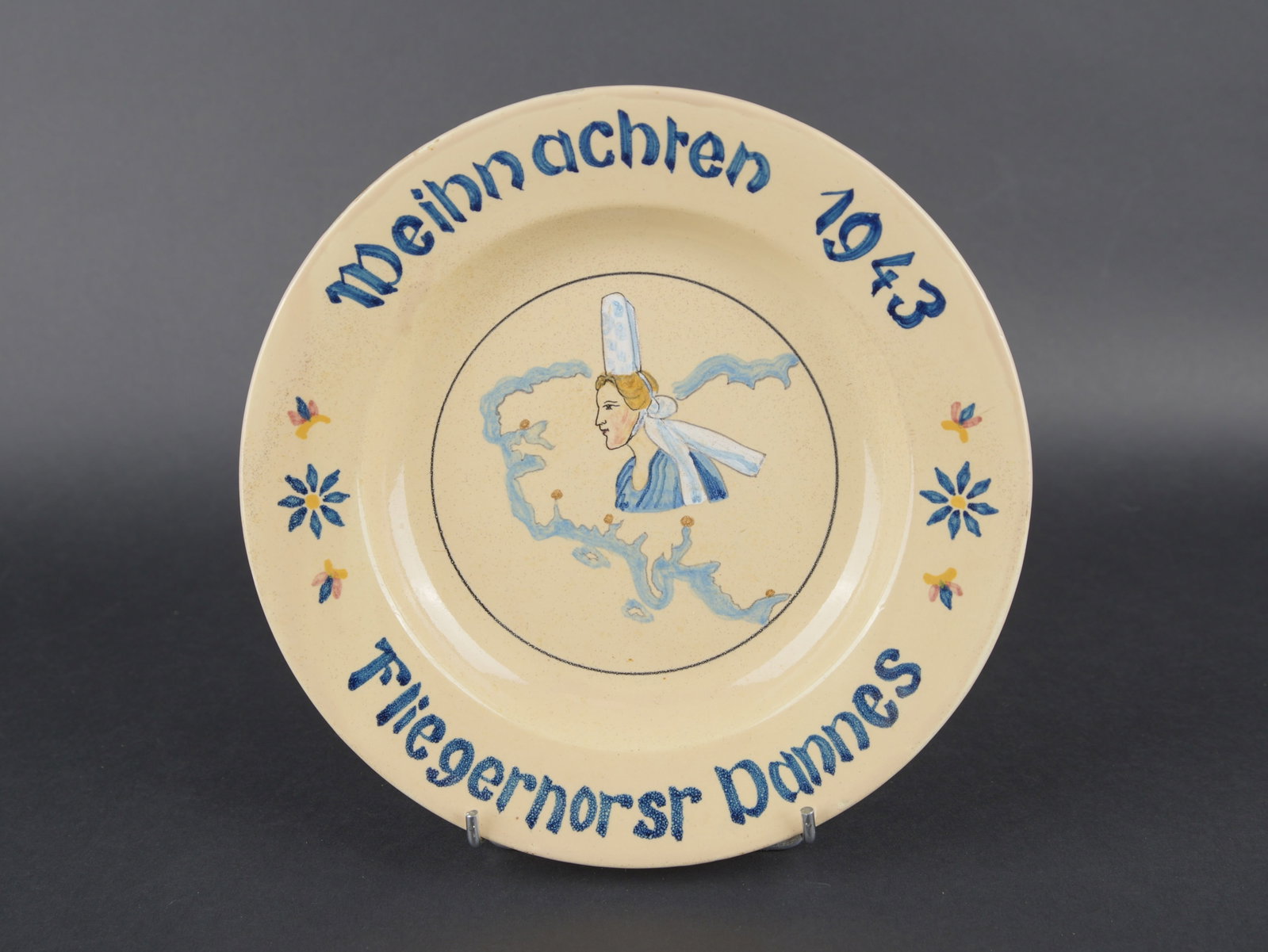 Assiette Fliegernor Vannes. Fliegerhorst Vannes plate.: Assiette Fliegernor Vannes. En ceramique peinte. Modele d assiette creuse. Decors d une bretonne sur une carte de la pointe Finistere. Marquages sur la bordure Weihnachten 1943 Fliegernrosr Vannes.