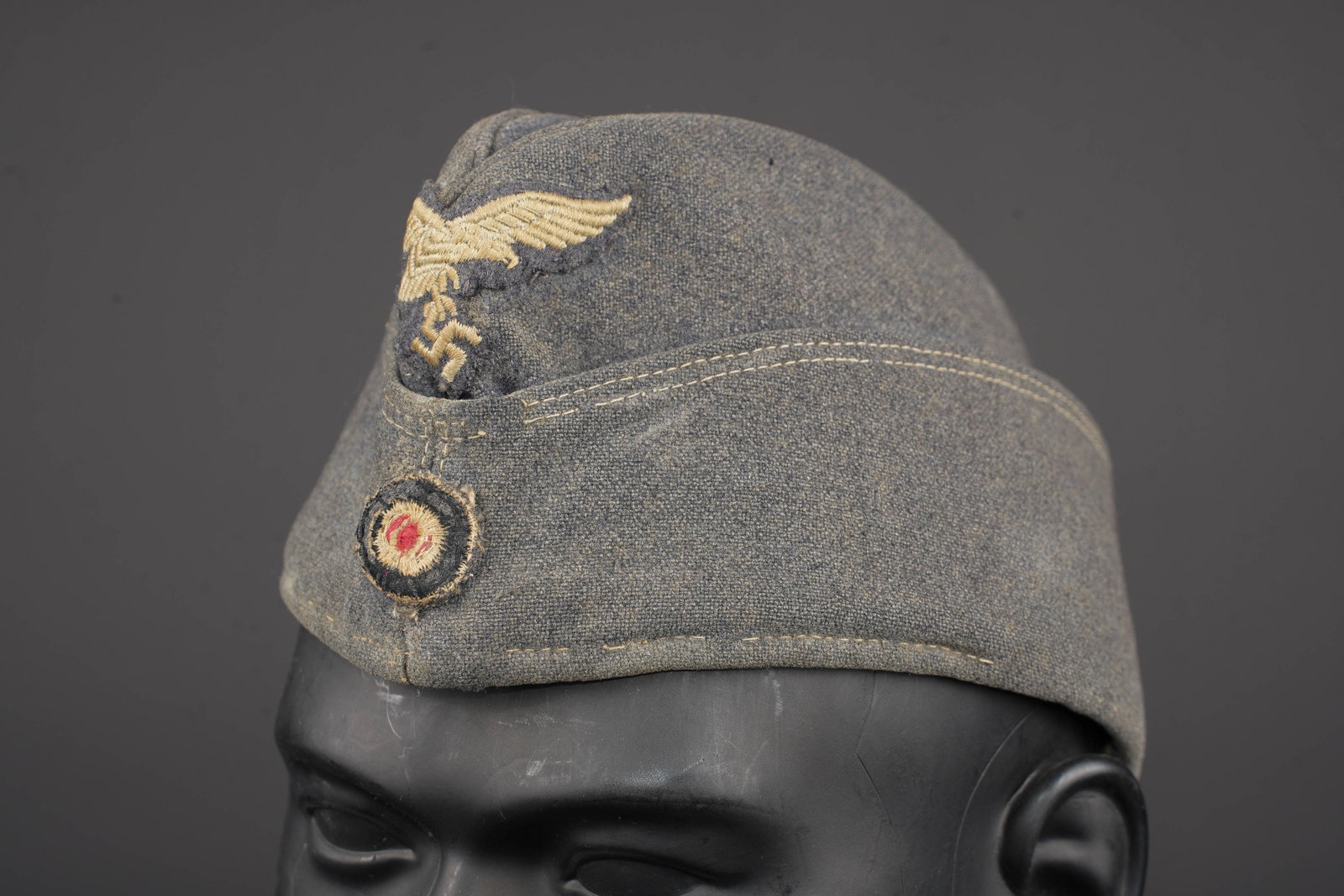 Calot de la Luftwaffe. Luftwaffe side cap.: Calot de la Luftwaffe. En drap gris/bleu. Insignes brodes, remontes. Interieur double en tissu coton gris. Les marquages sont illisibles. A noter une certaine usure et patine de la piece, ainsi que qu