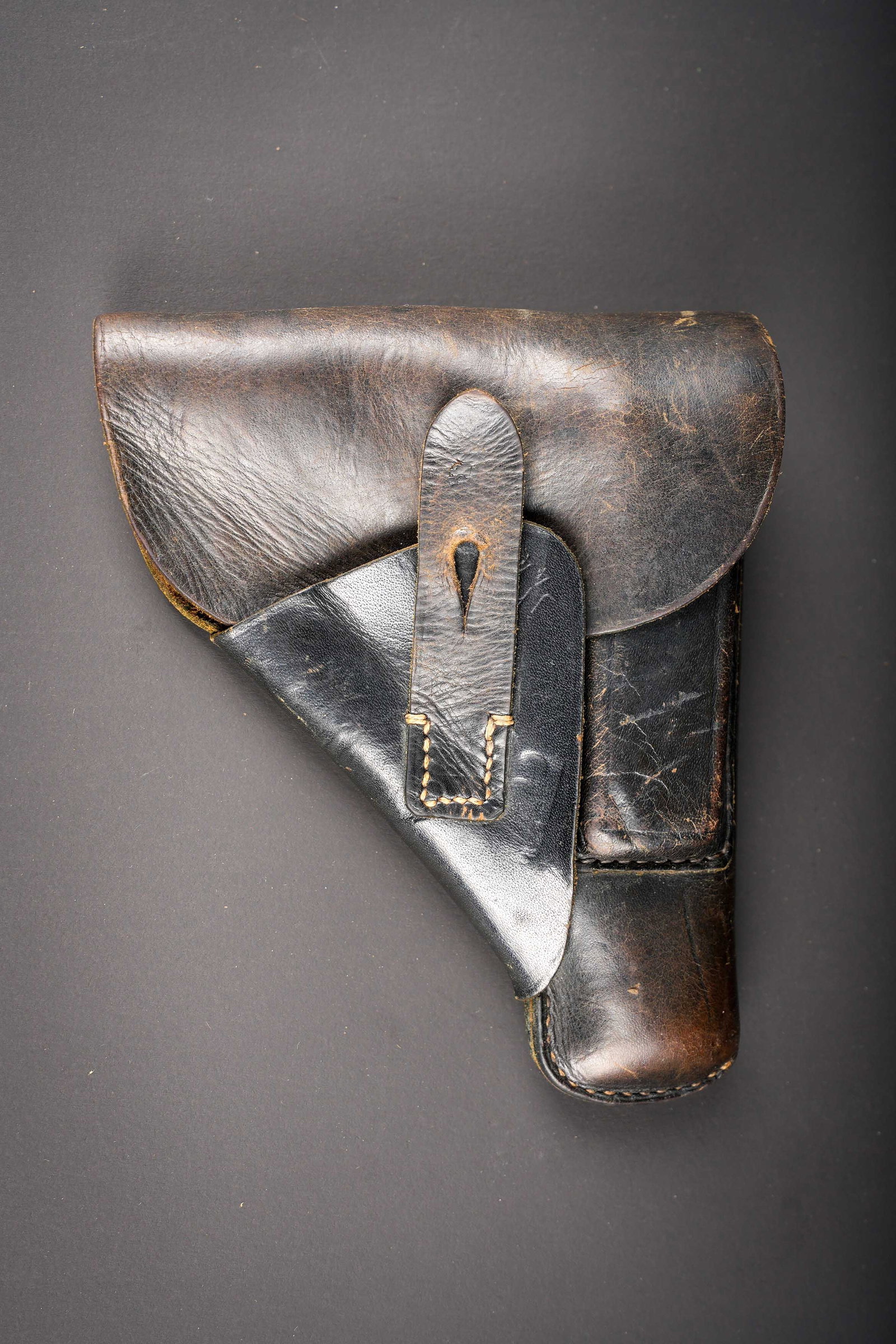 Holster de pistolet 7,65. German 7.65 mm pistol holster.: Holster de pistolet 7,65mm. En cuir noir. La sangle de fermeture est presente. Fabrication JHG 44. Le passant au dos est complet. A noter une certaine usure et patine de la piece. Etat II+. 7.65 mm