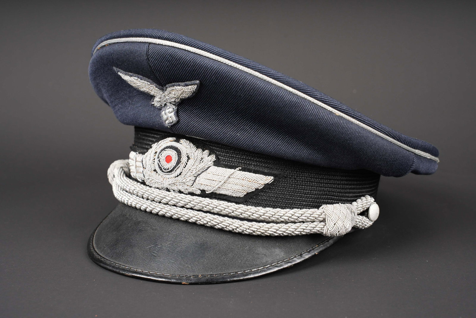 Casquette officier LW. Luftwaffe visor cap.: Casquette d officier de la Luftwaffe. En gabardine bleue foncee. Bandeau en mohair noir. Jugulaire d officier presente. Insignes en cannetille argent. Triple lisere argent du corps des officiers.