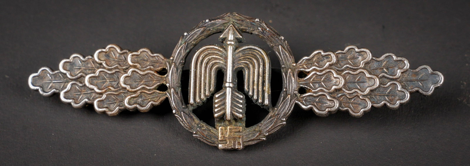 Frontluftspange. German Front Flight Clasp: Frontluftspange. En metal. Couleur argent, partie centrale couleur argent. Fabrication en deux parties. Attache complete. Fabrication HG Osan Dresden. A noter une certaine usure et patine de la piece.
