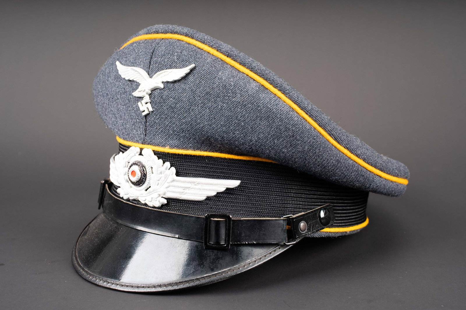 Casquette du personnel volant. German luftwaffe visor cap.: Casquette du personnel volant. Coiffe en drap gris/bleu. Triple lisere jaune du personnel volant ou parachutiste. Bandeau en mohair noir. Insignes metalliques. Les insignes n ont pas ete demontes