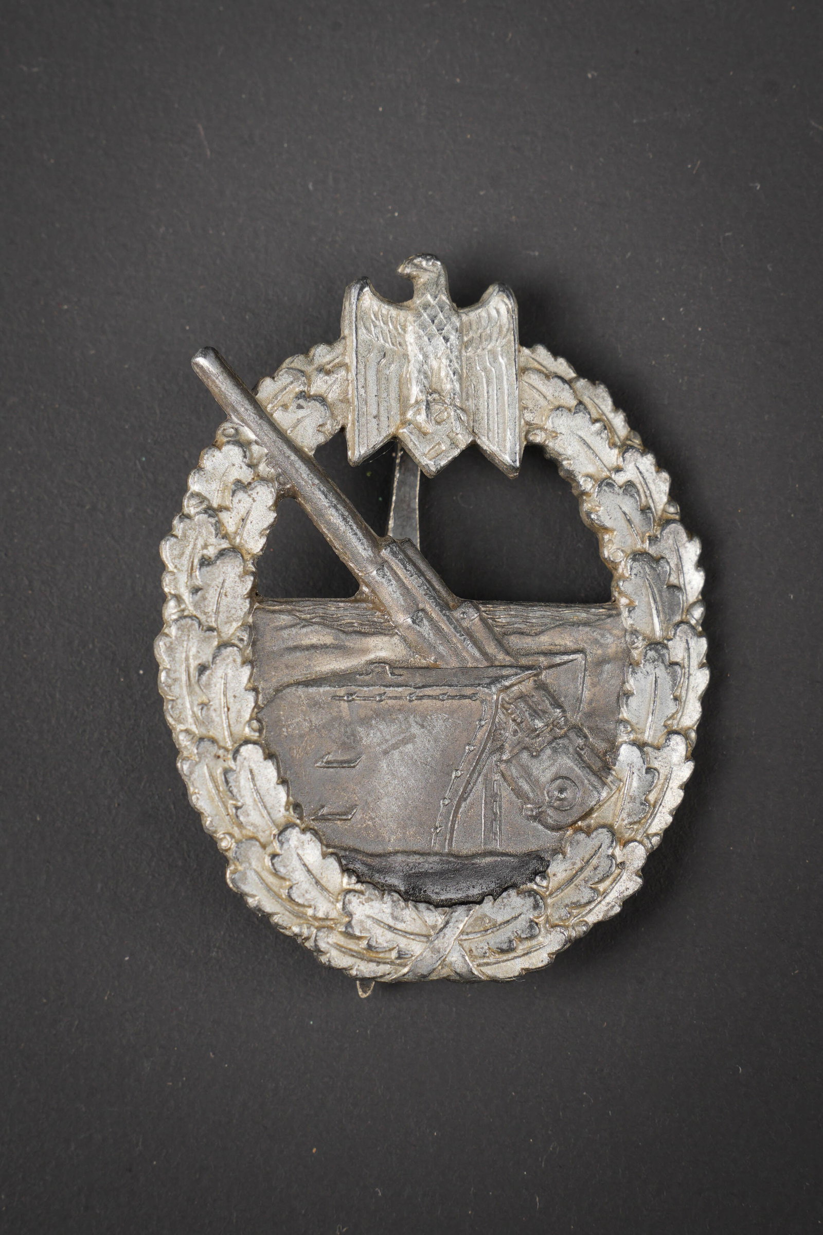 Insigne de l artillerie cotiere. Coastal Artillery insignia.: Insigne de l artillerie cotiere de la Kriegsmarine. En metal, couleur argent a 70%. Attache complete. Marquages FEC Otto Placzek Berlin CE Junker. A noter une certaine usure et patine de la piece. Eta