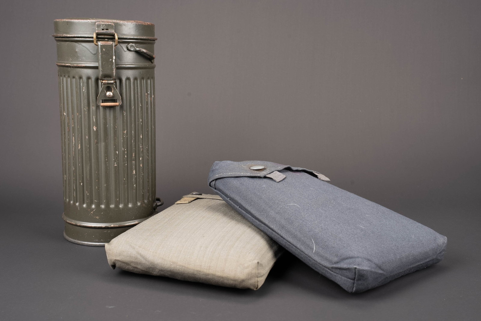 Ensemble anti-gaz. German gas mask accessories: Ensemble anti-gaz. Comprenant un boitier en metal. Modele long, peinture Feldgrau a 70%. Vide. Toutes les sangles sont absentes. Quelques bosses visibles. Date 1938. Un housse pour gasplane en tissu F