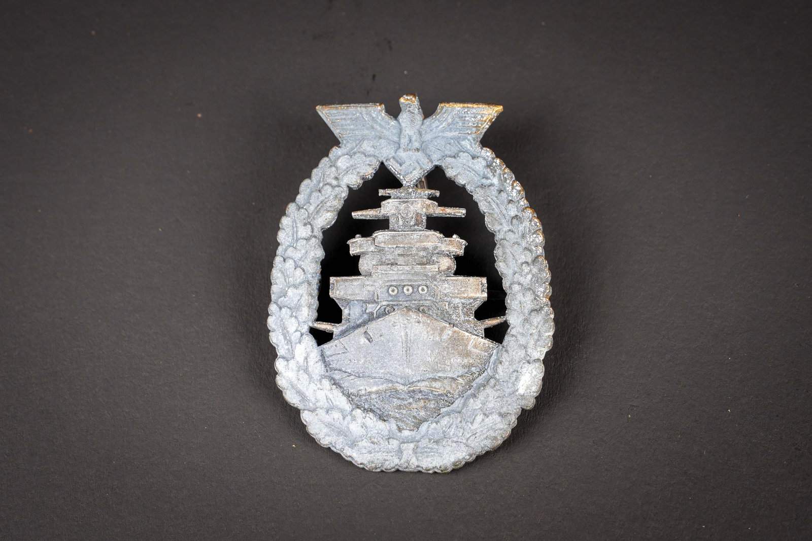Flotten-Kriegsabzeichen. German Kriegsmarine insignia: Flottenkriegsabzeichen. En metal. Couleur or a 2%. Attache horizontale complete. Le petit crochet est egalement present. Sans marquages visibles. A noter une certaine usure et patine de la piece. Etat