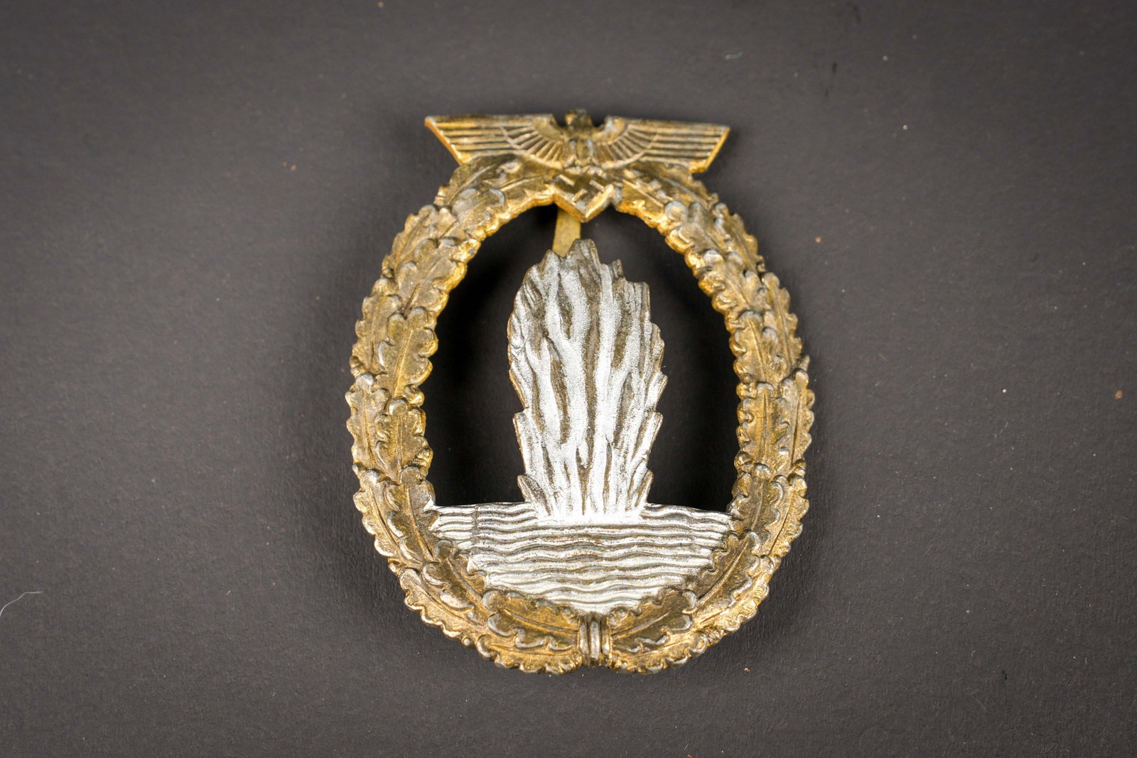 Kriegsabzeichen fur Minensuch-, U-Boot-Jagd- und Sicherungsverbande. German insignia: Kriegsabzeichen fur Minensuch-, U-Boot-Jagd- und Sicherungsverbande. Belle fabrication bombee. Pourtour de feuille de chene couleur or a 70%. Partie centrale couleur argent a 70%. Attache complete. Fa