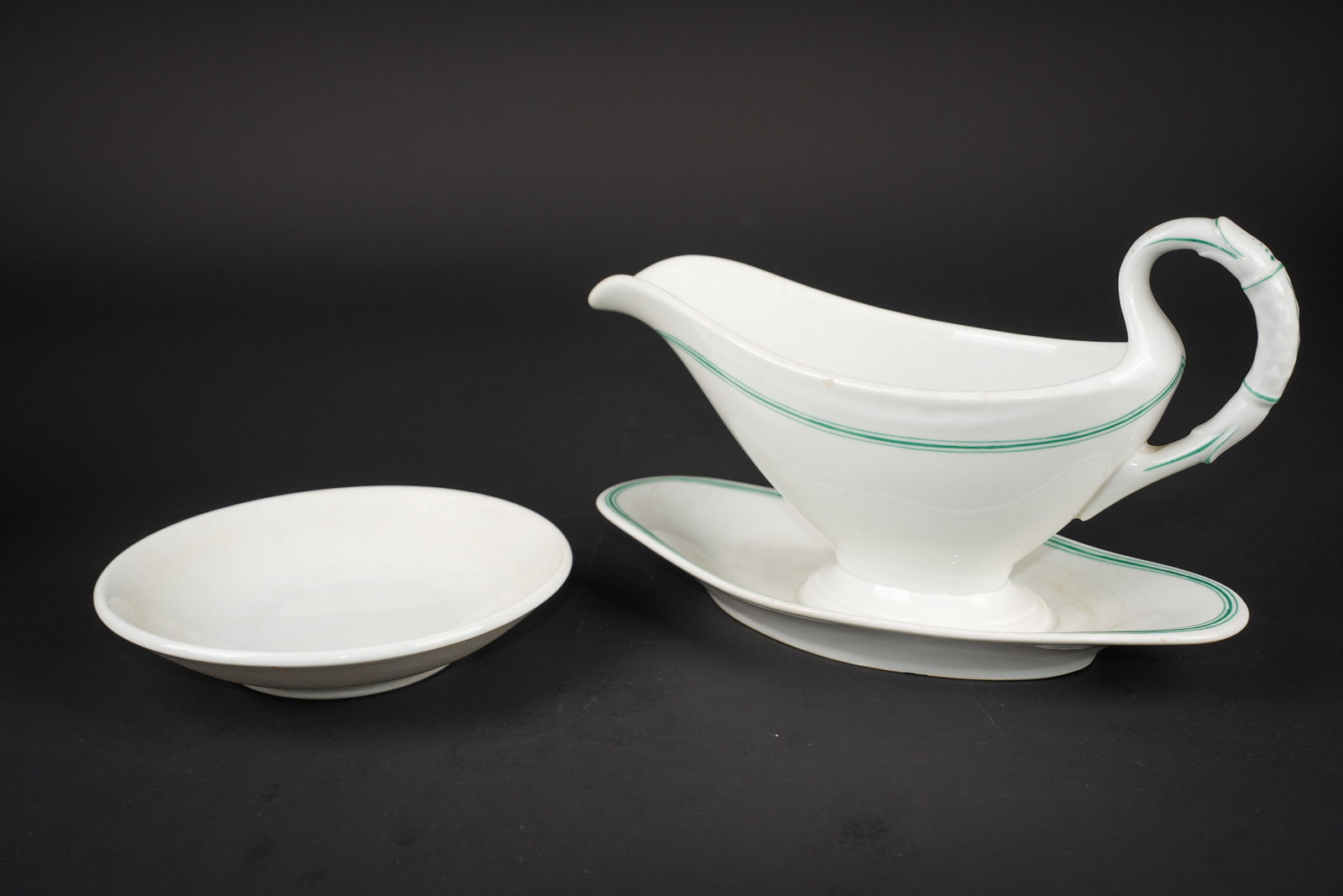 Sauciere Kriegsmarine. Kriegsmarine sauce boat.: Sauciere de la Kriegsmarine. Tres belle sauciere d un modele non reglementaire. En ceramique blanche, double lisere vert. Beau marquage de la Kriegsmarine, sans date, longueur environ 26,5 cm. On y jo