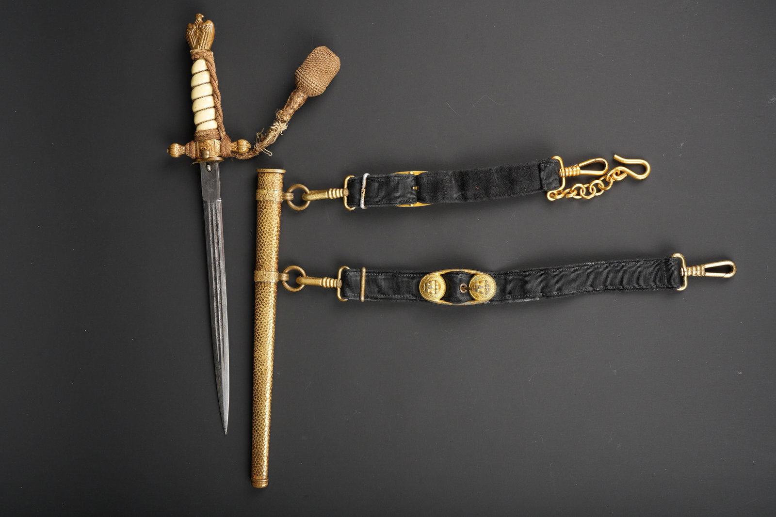 Dague Kriegsmarine. Kriegsmarine dagger.: Dague de la Kriegsmarine. Pommeau en metal couleur or, representant l aigle allemand. Poignee en cellulod blanche, filigrane complet. Dragonne couleur or nouee de maniere reglementaire, celle-ci est p