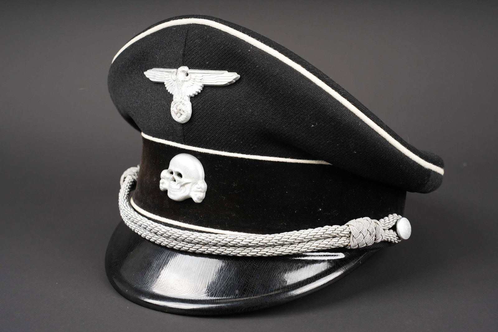 Casquette Allgemeine SS. Allgemeine SS visor cap.: Casquette de l Allgemeine SS. En drap noir. Triple lisere blanc. Bandeau en velours noir. Insignes couleur argent. Les insignes n ont pas ete demontes afin de verifier les attaches. Jugulaire d