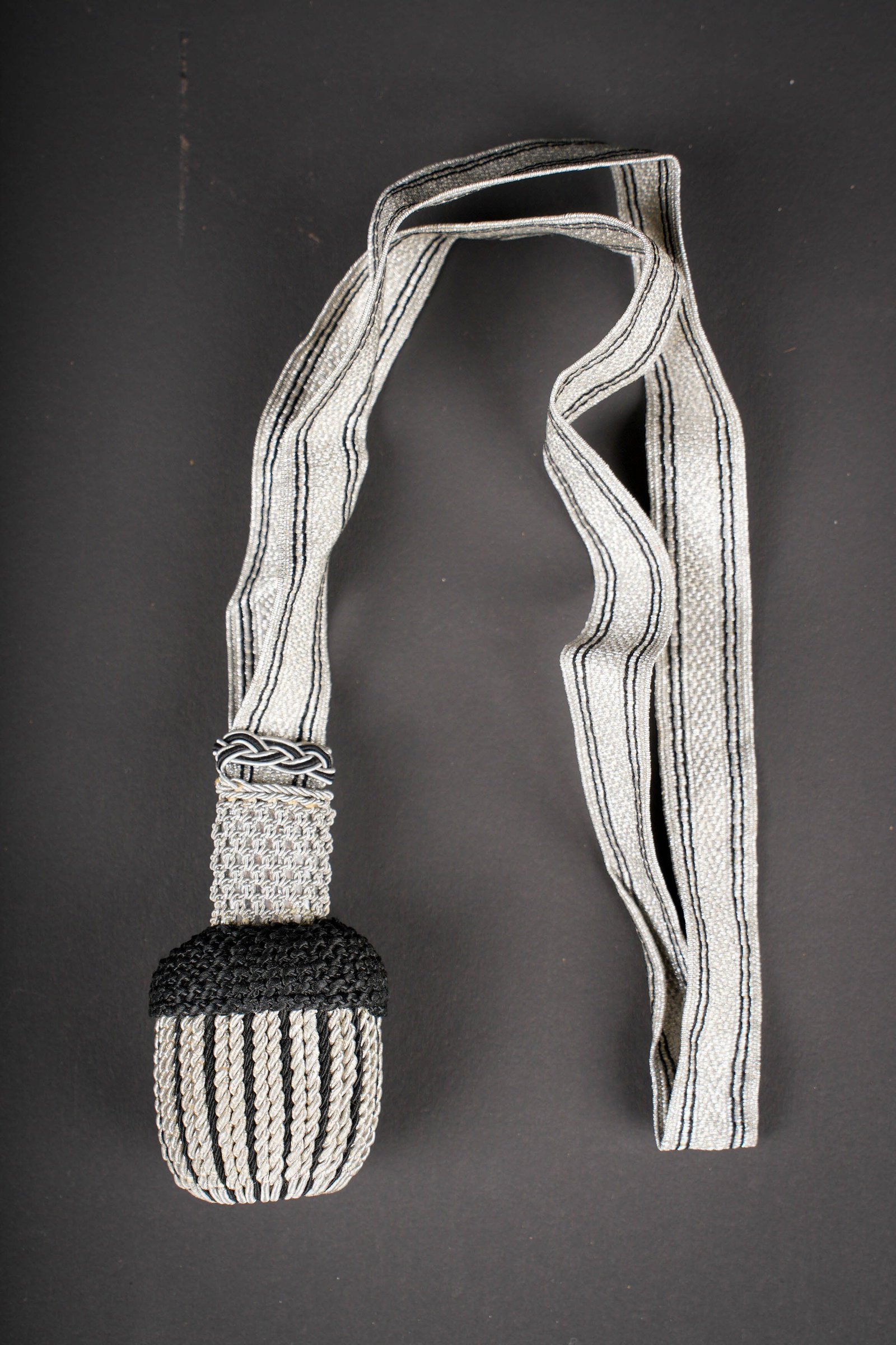 Dragonne SS. SS portepee.: Dragonne SS. Passementerie couleur argent. Double lisere en fil noir. Partie superieur du gland en cannetille tresse argent. Modele sans rune SS. Gland en fils noir et argent. A noter une certaine usu