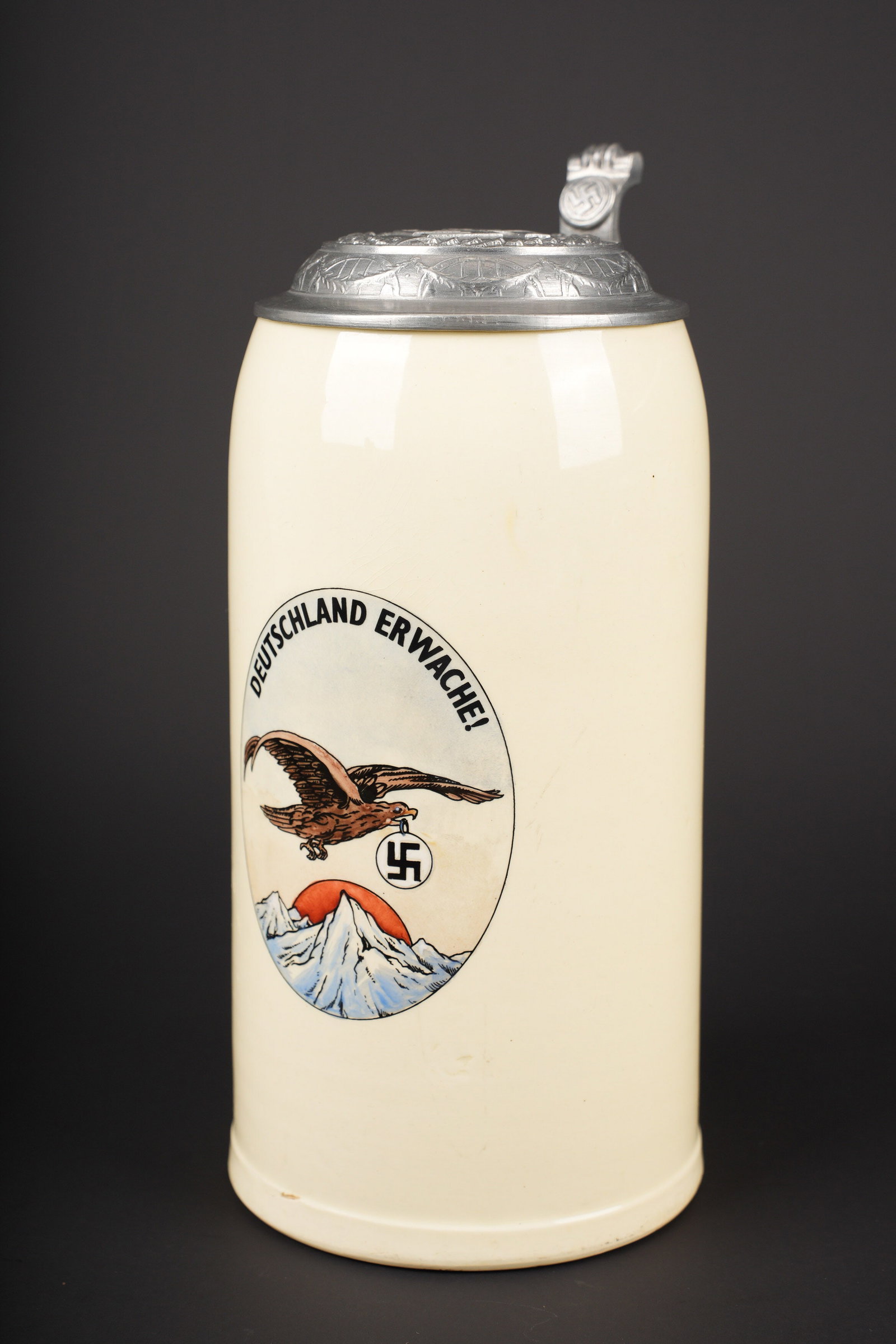 Chope allemande. German tankard.: Chope allemande. En ceramique emaillee. Couvercle disposant d un insigne national en relief. Dessin d un aigle portant l insigne national par les montagne au soleil couchant. Marquages Deutschland