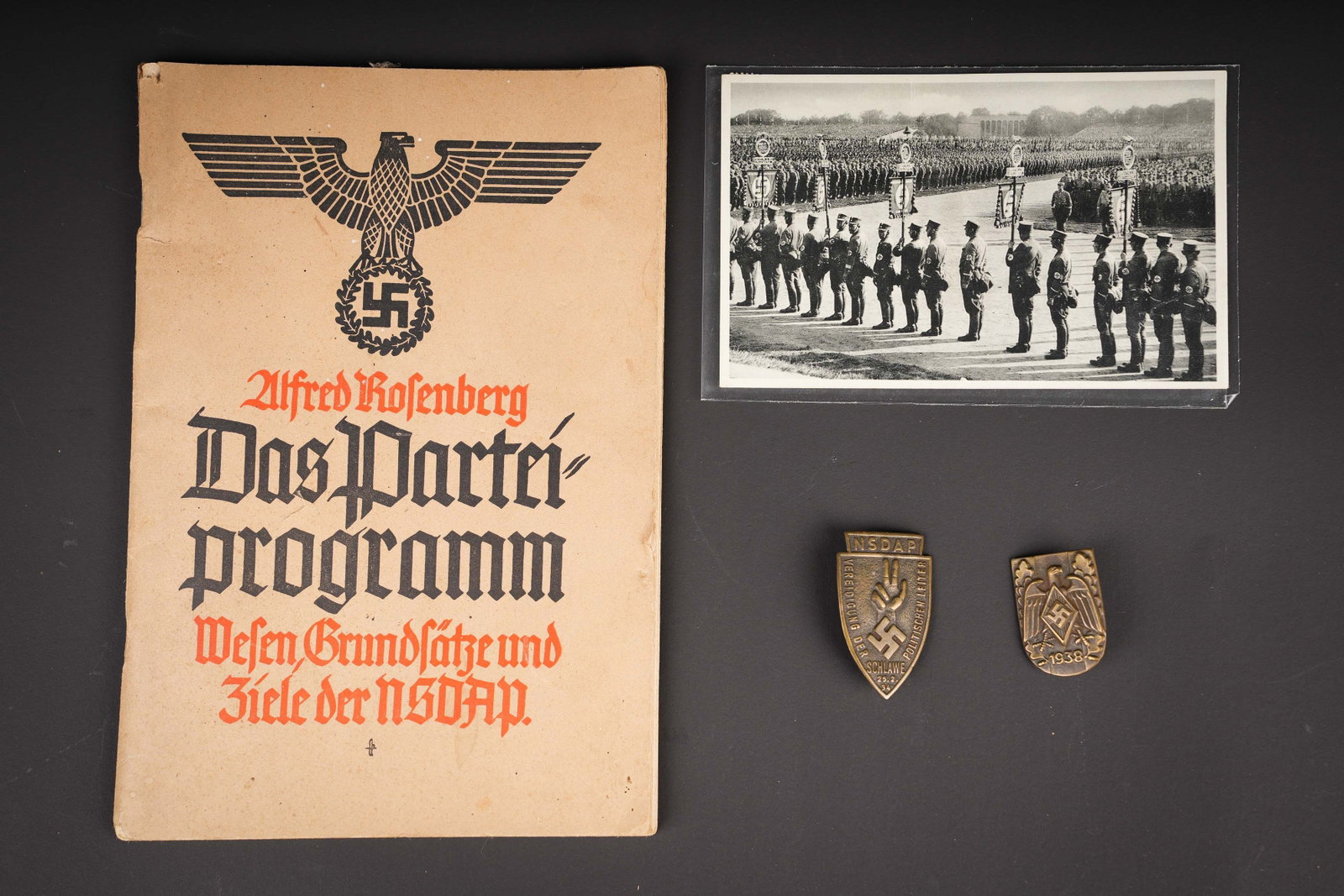 Ensemble de souvenirs NSDAP. NSDAP souvenir collection.: Ensemble de souvenirs NSDAP. Un programme du Parti par Alfred Rosenberg, edition de 1940. Une carte postale de Nuremberg. Un insigne de Vereidigung der Politischen Leiter, Schlawe 1934. On joint un