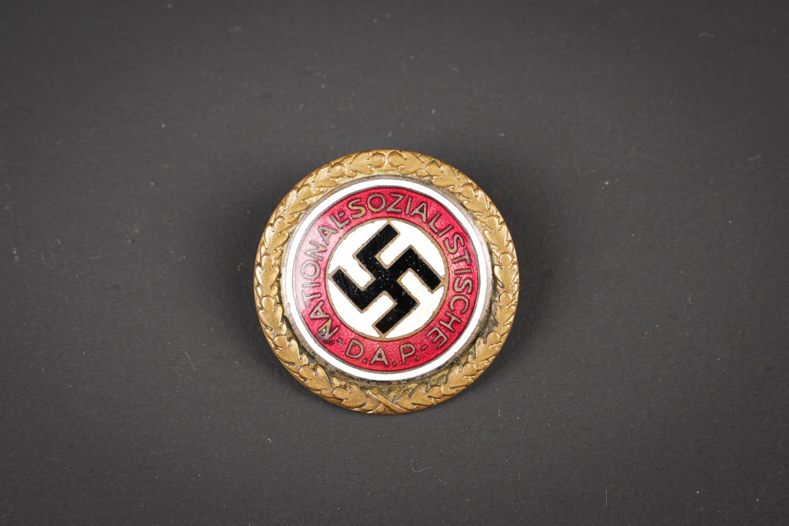 Goldenes Ehrenzeichen der NSDAP. Golden Party Badge of the NSDAP: Goldenes Ehrenzeichen der NSDAP. En metal emaille. Bordure de feuille de chene couleur or. Attache complete. Fabrication Deschler & Son Munchen. Numero 9612. Diametre 3,1 cm. A noter une certaine