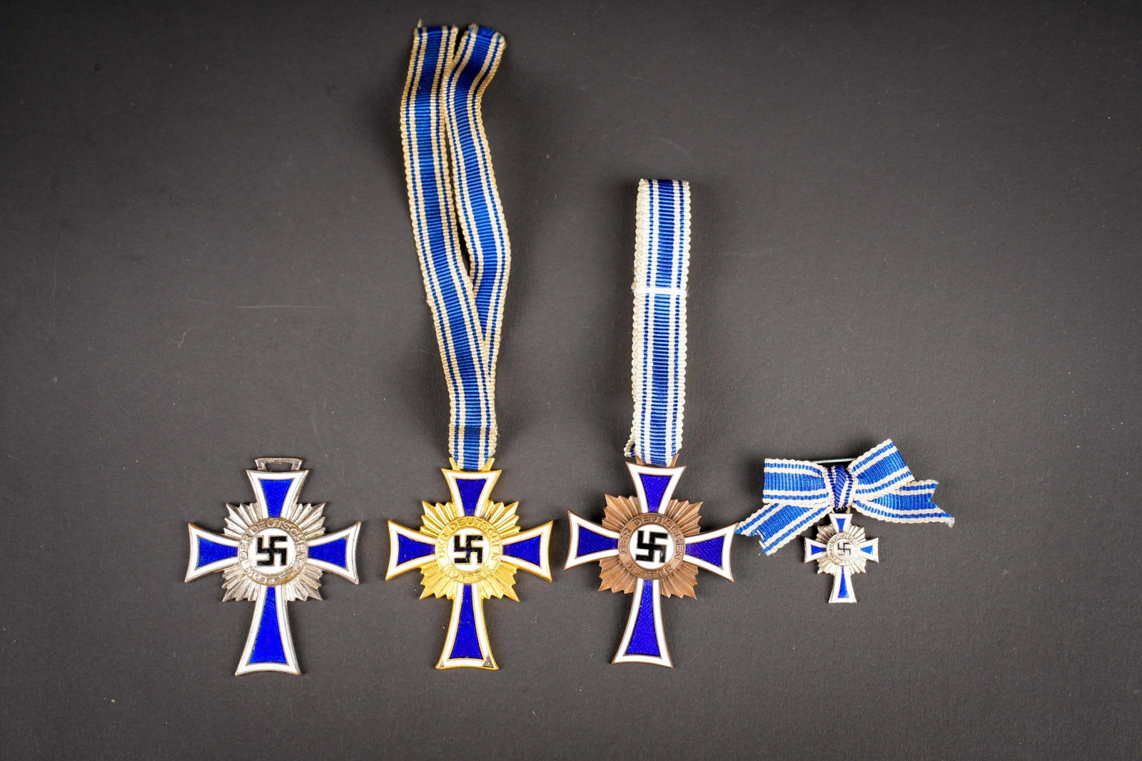 Mutterkreuz. Mother?s Cross: Mutterkreuz. Comprenant une croix des meres couleur bronze, en metal emaille. Datee 1938, ruban complet et nouee d origine. Une croix des meres en metal emaille et couleur or, ruban present, datee