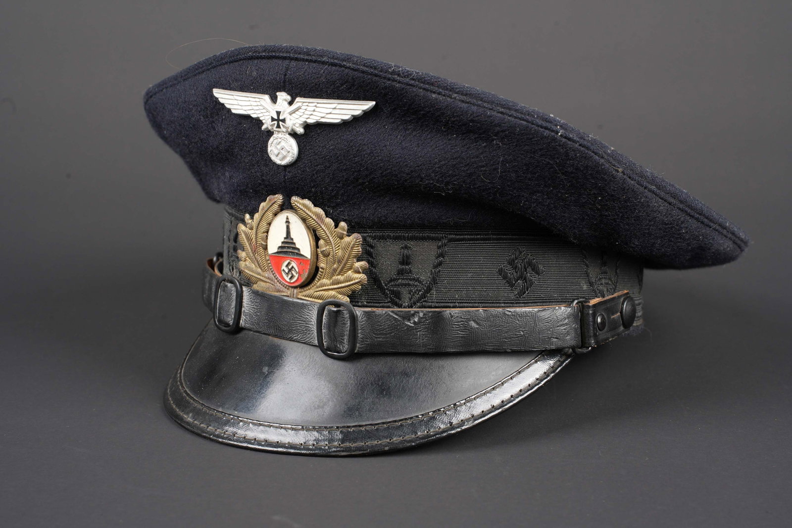 Casquette ancien combattants. German Veteran visor cap.: Casquette de l association des anciens combattants. En drap noir. Aigle en aluminium. Insigne de l association des anciens combattant en metal peint. Bandeau en mohair noir, disposant des insignes de