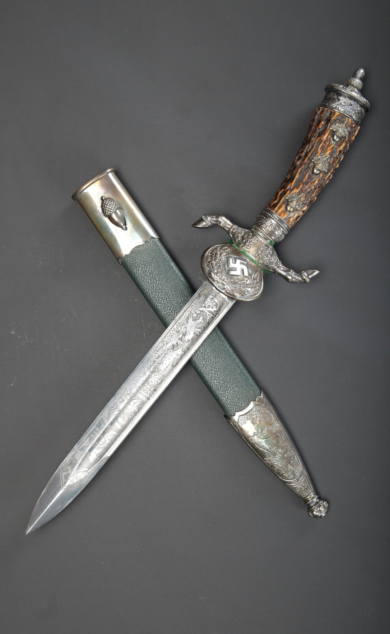 Dague de chasse. German Dagger.: Dague de chasse allemande. Garniture en metal couleur argent, a decors de feuilles de chene. Poignee en fausse corne, disposant de trois glands en metal argente. Garde en S a decors de sabots de