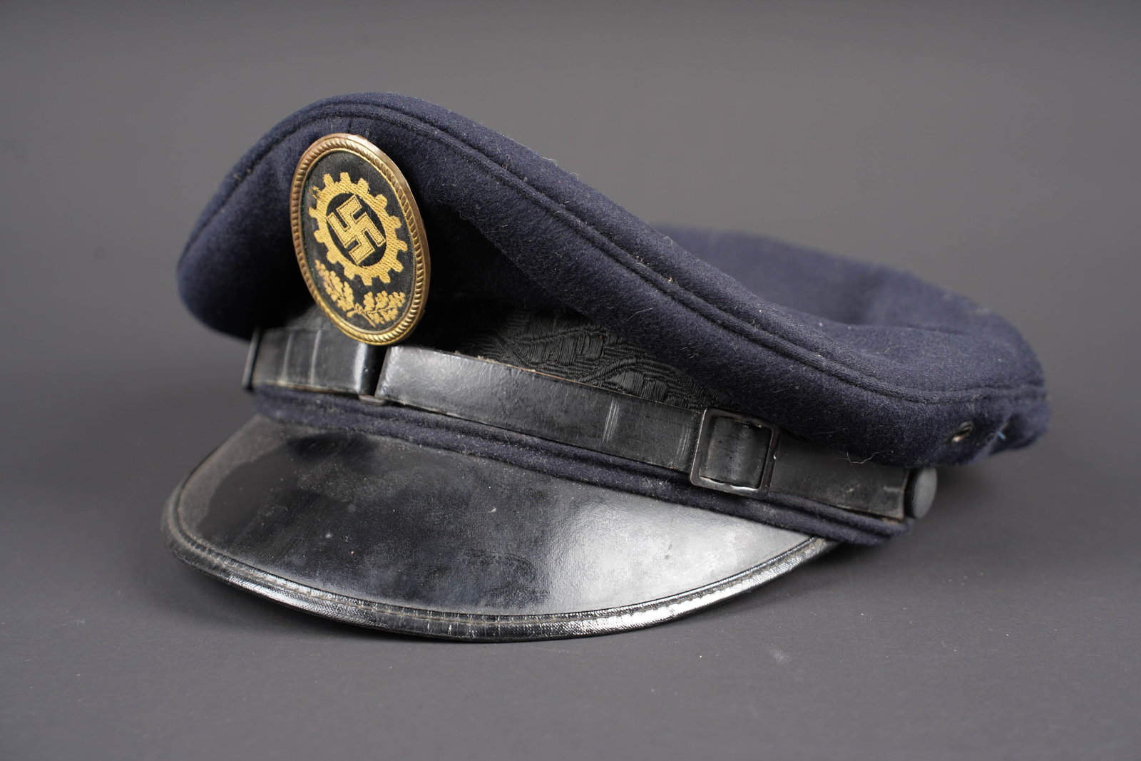 Casquette du DAF. DAF visor cap.: Casquette du DAF. En drap noir. Bandeau en tissu noir a decors de feuilles de chene. Jugulaire complete. Insigne du DAF en tissu et monte sur un support en metal. L insigne n a pas ete demonte afin
