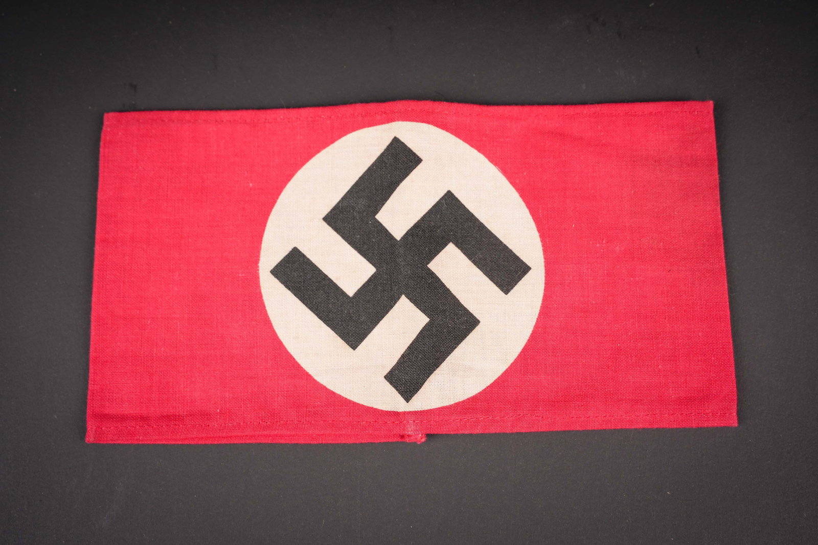 Brassard allemand. German armband.: Brassard allemand. En tissu coton rouge. Insigne national imprime directement sur la bande de tissu rouge. Sans marquages visibles. A noter une legere usure et patine de la piece. Etat I-. German