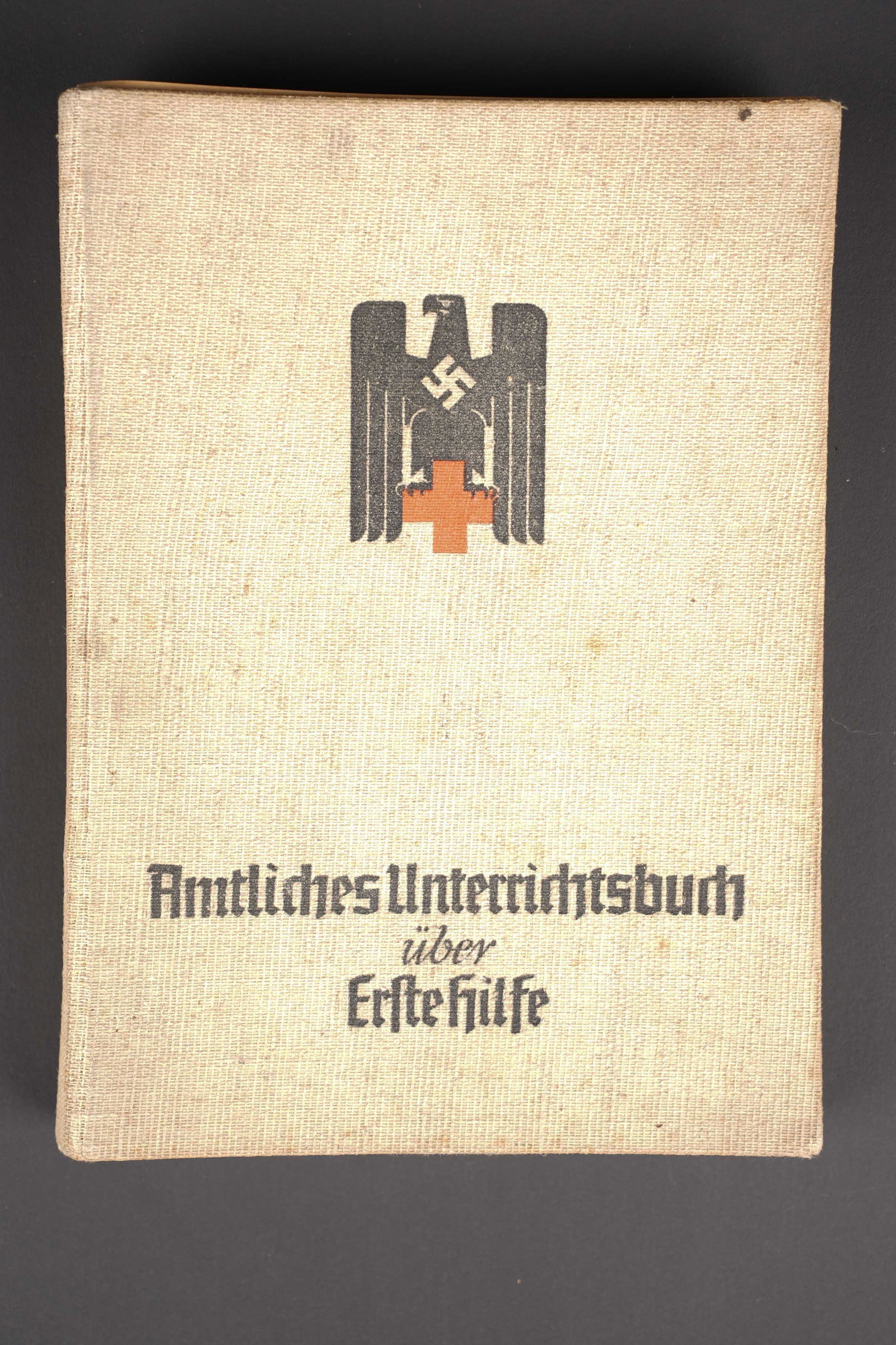 Livre de premier secours DRK. DRK First Aid Manual.: Livre de premiers secours DRK. Couverture en carton recouverte d un tissu gris. Bel insigne DRK. Intitule Amtliches Unterrichtsbuch uber Erste Hilfe. Tampon du Kreis Graslitz. Date 1938. A noter une