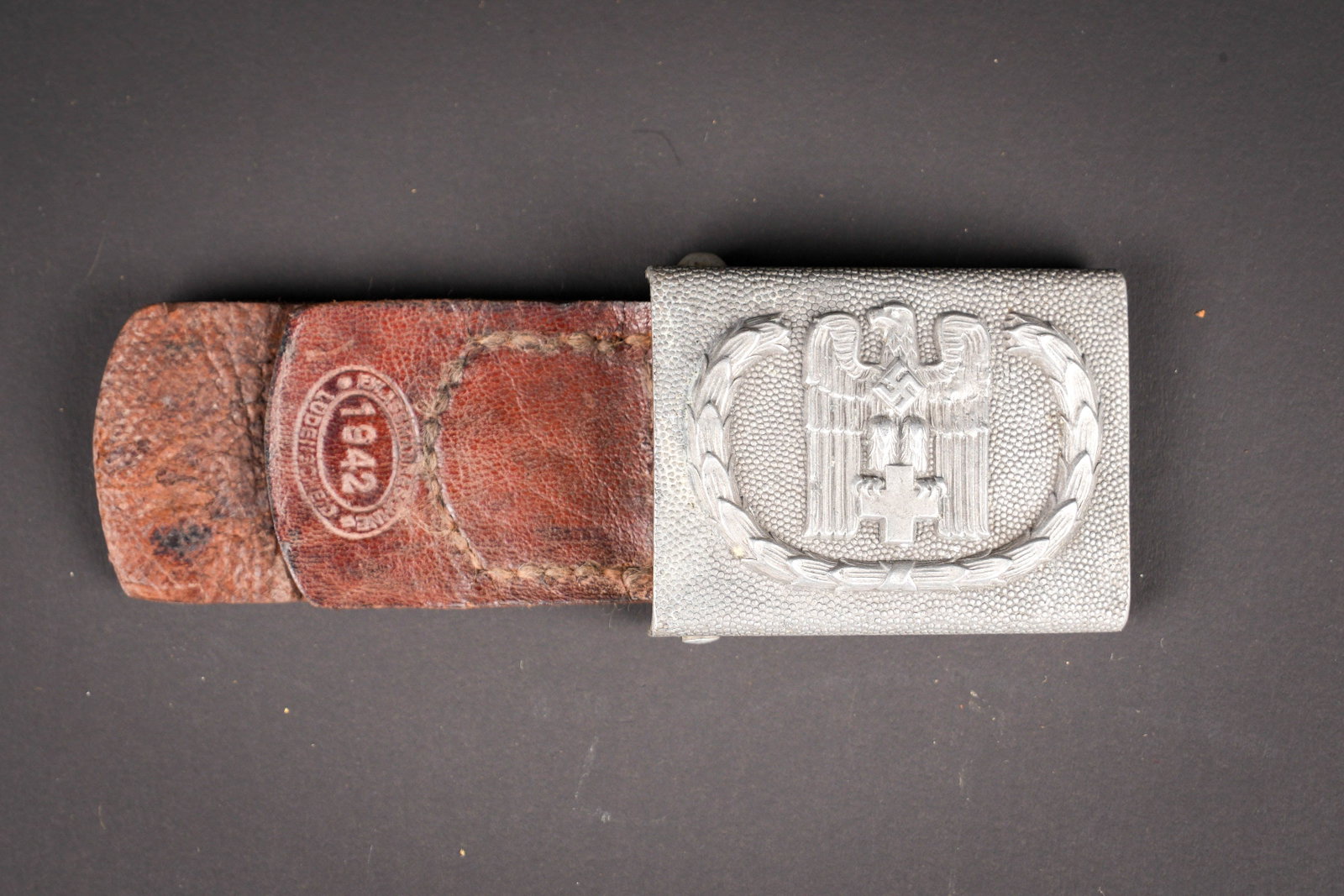 Boucle de ceinturon DRK. German Red Cross Belt Buckle.: Boucle de ceinturon DRK. En aluminium grenele. Marquages 39 Ges Gesch. Patte en cuir recousue. Datee 1942. A noter une certaine usure et patine de la piece. Etat II+. DRK belt buckle. Pebbled