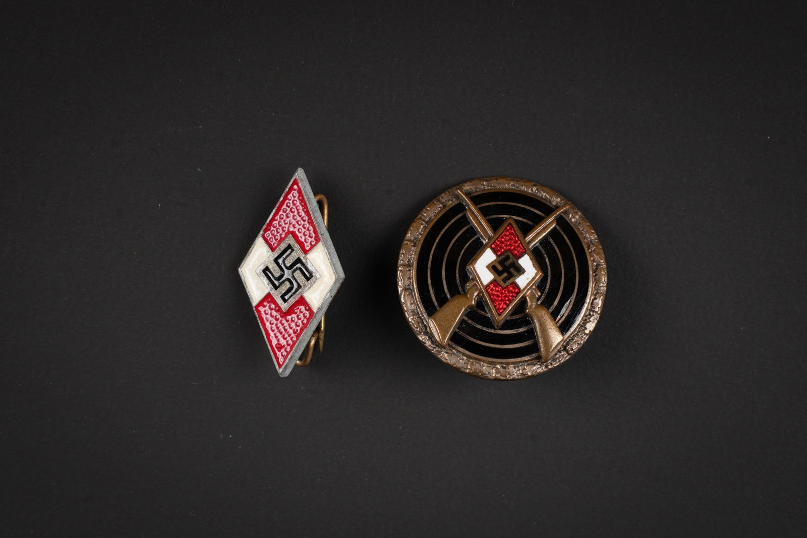 Insignes Hitlerjugend. Hitler Youth insignias: Insignes de la Hitlerjugend. Comprenant un insigne de coiffure en metal peint. Attache complete, marquages visibles. Un insigne de tireur de la Hitlerjugend, en metal emaille, couleur bronze. Attache