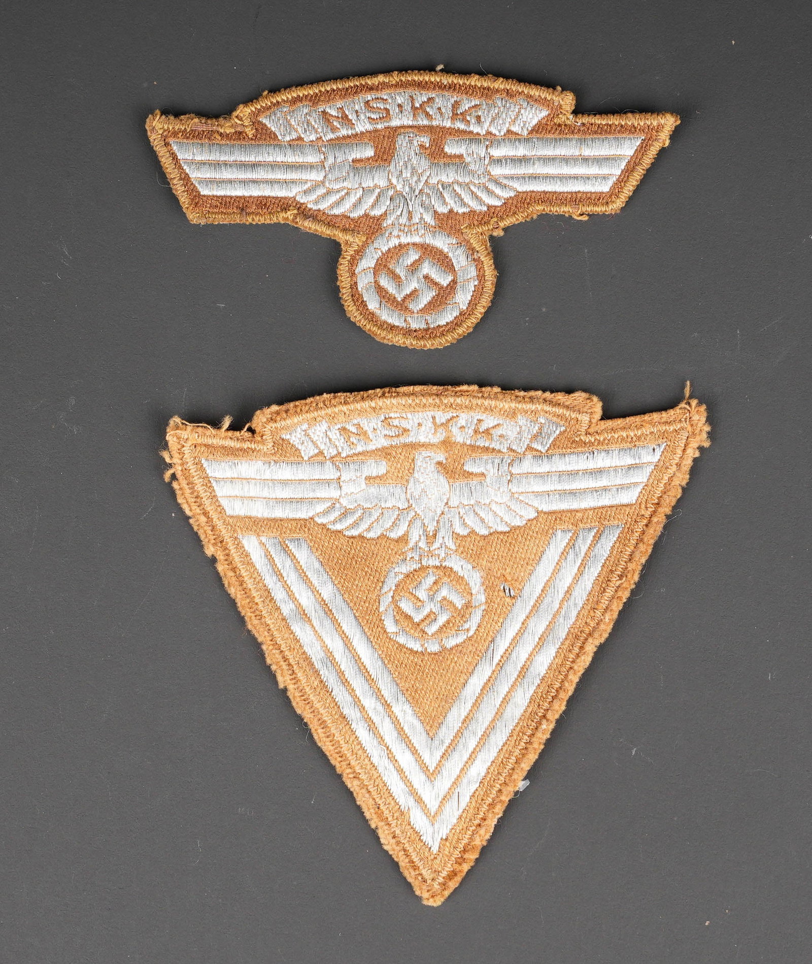 Insignes de manche NSKK. NSKK sleeve insignia.: Insignes de manche NSKK. Comprenant un aigle de manche brode argent sur fond brun. Reste d etiquette RZM illisible. Un insigne de grade NSKK brode argent sur fond brun, etiquette RZM M4/374, numero 39