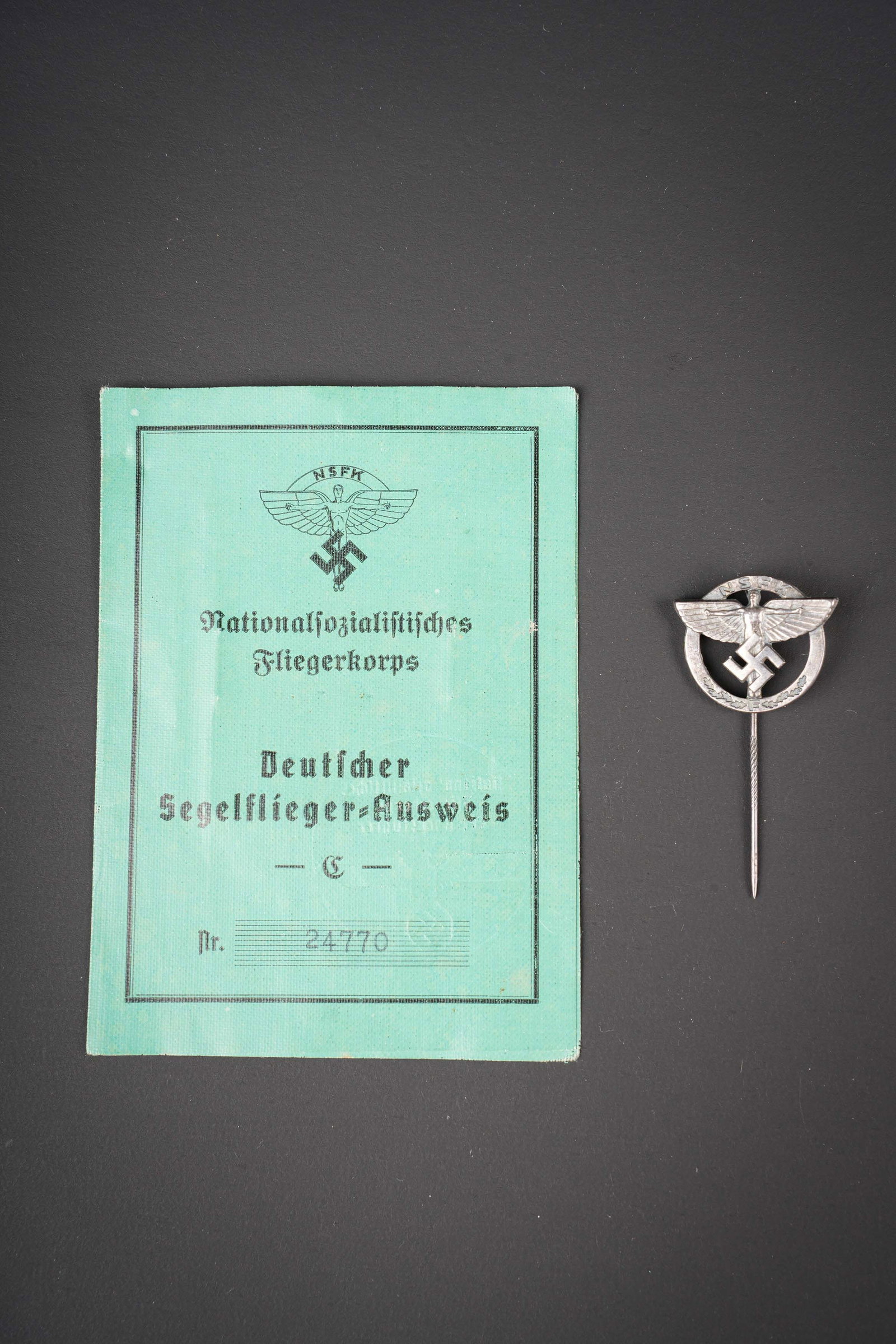 Insigne NSFK. NSFK insignia.: Insigne NSFK. Epinglette en metal, couleur argent. Attache complete. Marquages Ges Gesch au dos. Livret Deutscher Segelflieger Ausweis, numero 24770, photo d identite presente. Fait a Peine le 13