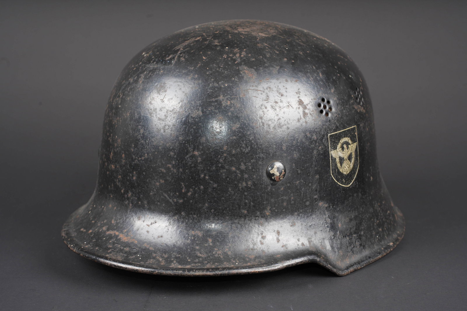 Casque Feuerschutzpolizei. Feuerschutzpolizei helmet.: Casque Feuerschutzpolizei. Modele 34. Peinture noire a 70%. Modele sans cimier. Les insignes sont des decalcomanies, presents a 30 et 80%. Jugulaire en cuir marron. La nuquiere amovible est absente.
