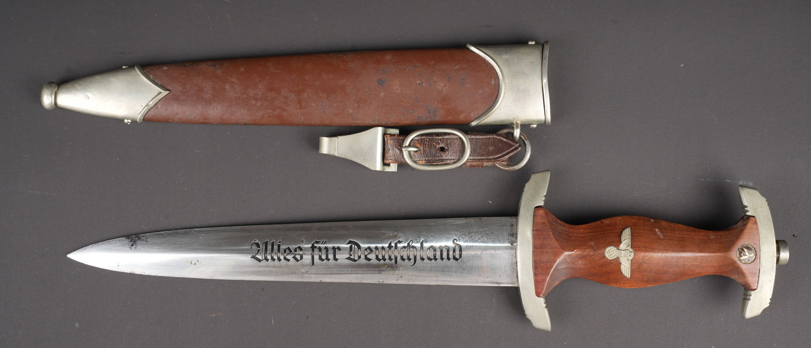Dague SA. German SA dagger.: Dague SA. Garnitures metalliques. Poignee en bois marron. Insignes metalliques visiblement recolles. Garde portant le marquage BO. Belle lame portant la mention Alles Fur Deutchland. Fabrication